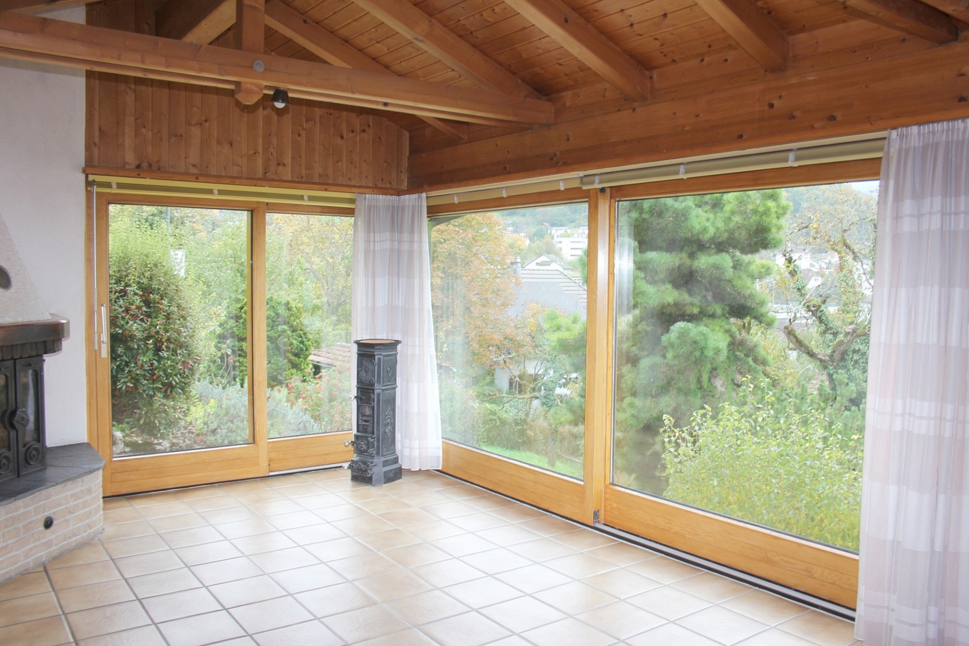 Heller Wohnraum mit großen Holzfenstern und Kamin