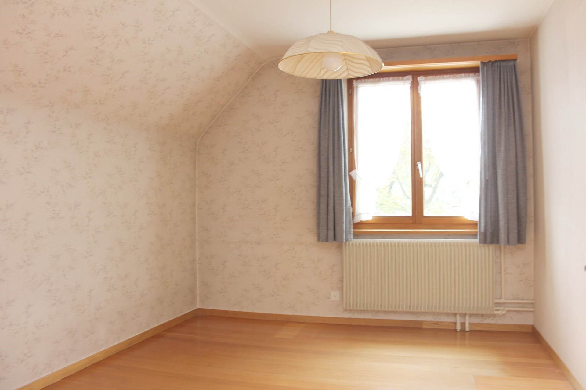 Leerer Dachzimmerraum mit Fenster und Heizkörper