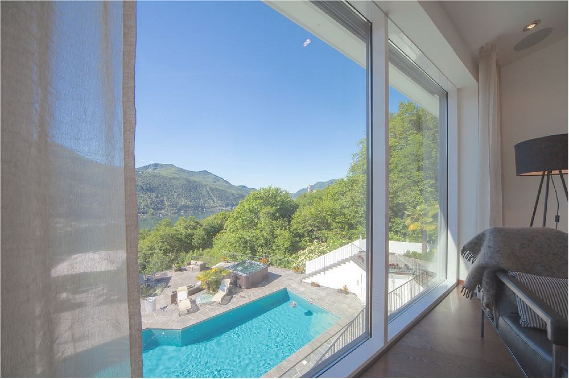 Blick aus einem Innenraum auf Pool und Berglandschaft
