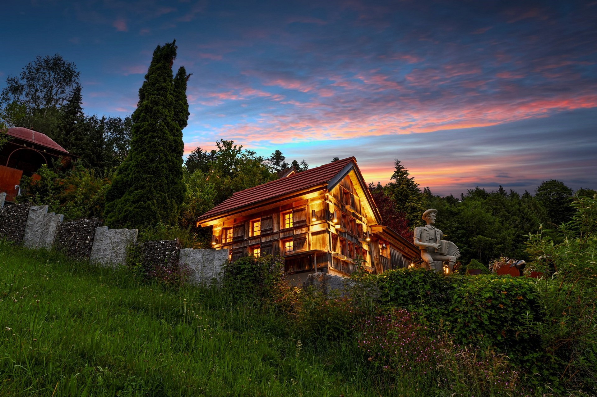 Rustikales Holzhaus im Garten bei Sonnenuntergang