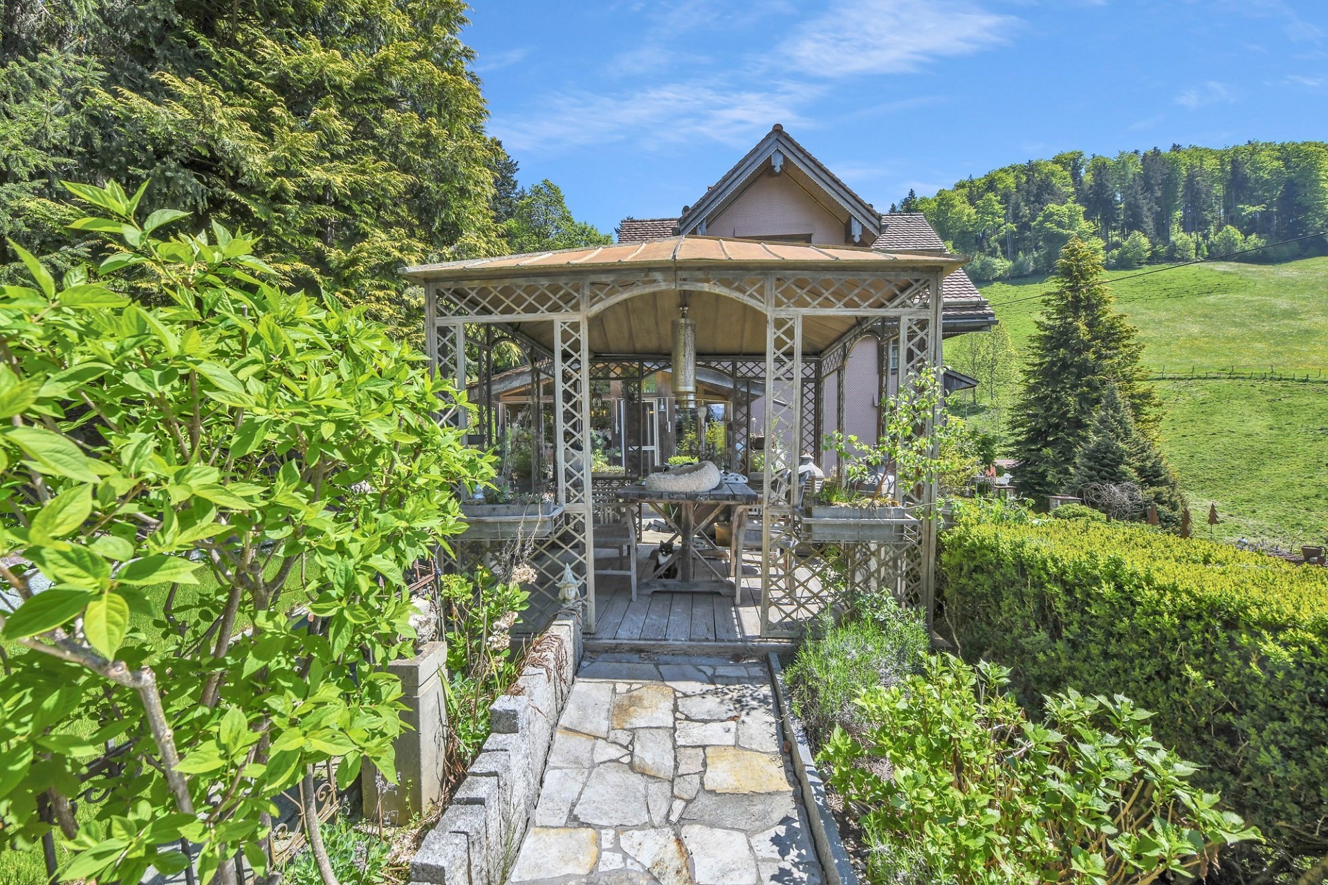 Gartenpavillon mit Terrasse vor ländlicher Hanglage