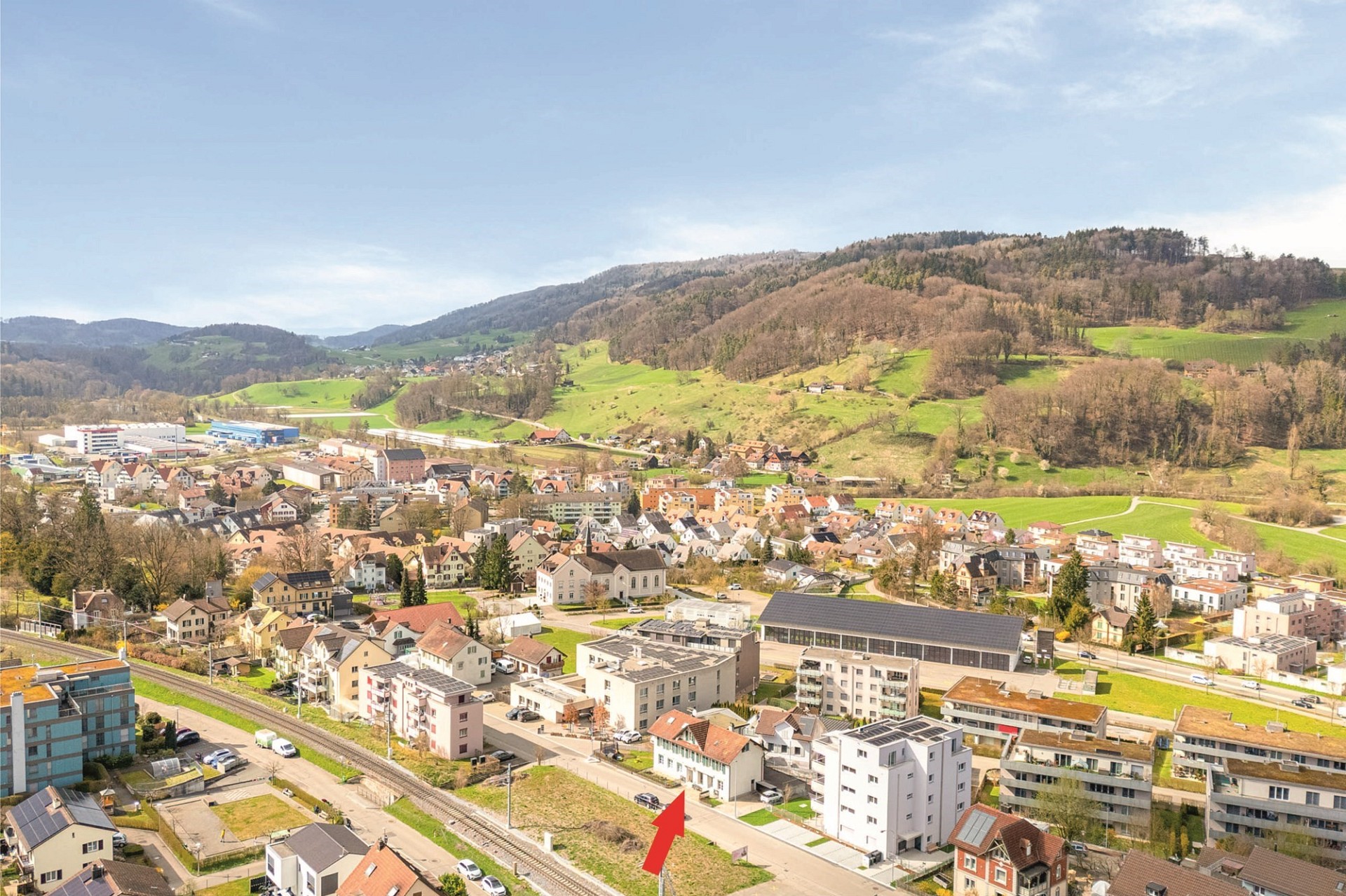 Weitblick über eine Kleinstadt und grüne Hügellandschaft