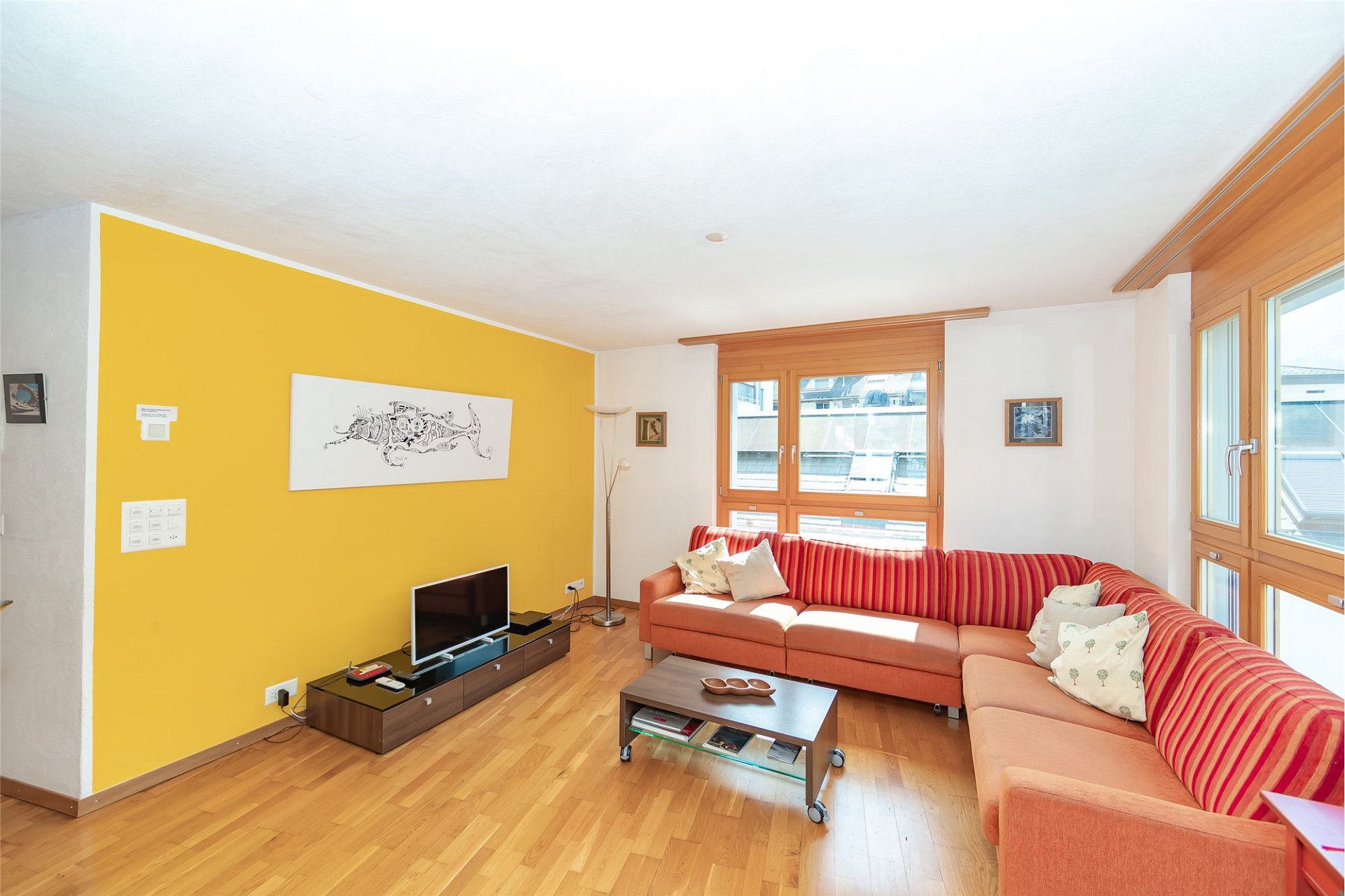 Helles Wohnzimmer mit Ecksofa und großen Fenstern