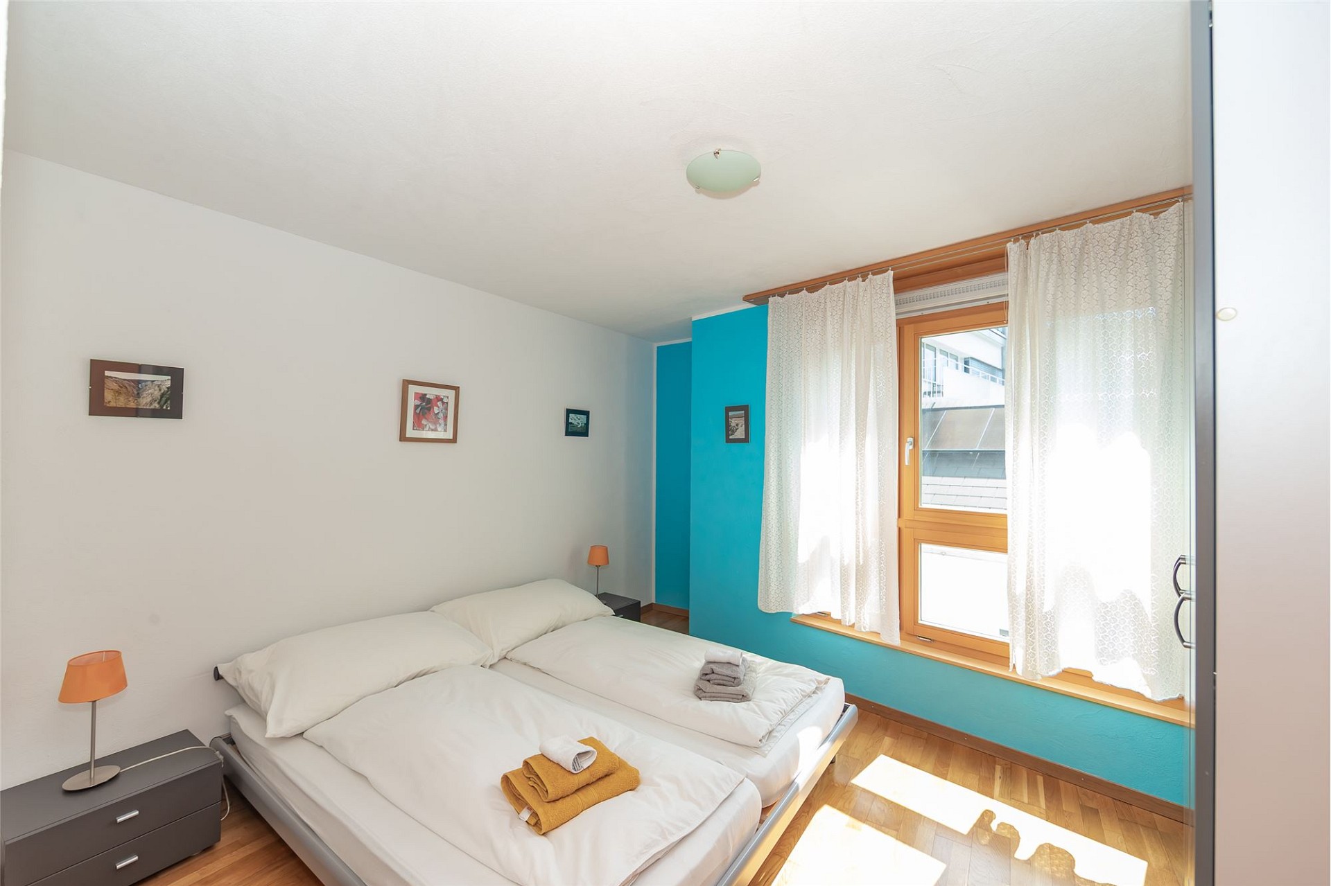 Helles Schlafzimmer mit Doppelbett und farbig akzentuierter Wand