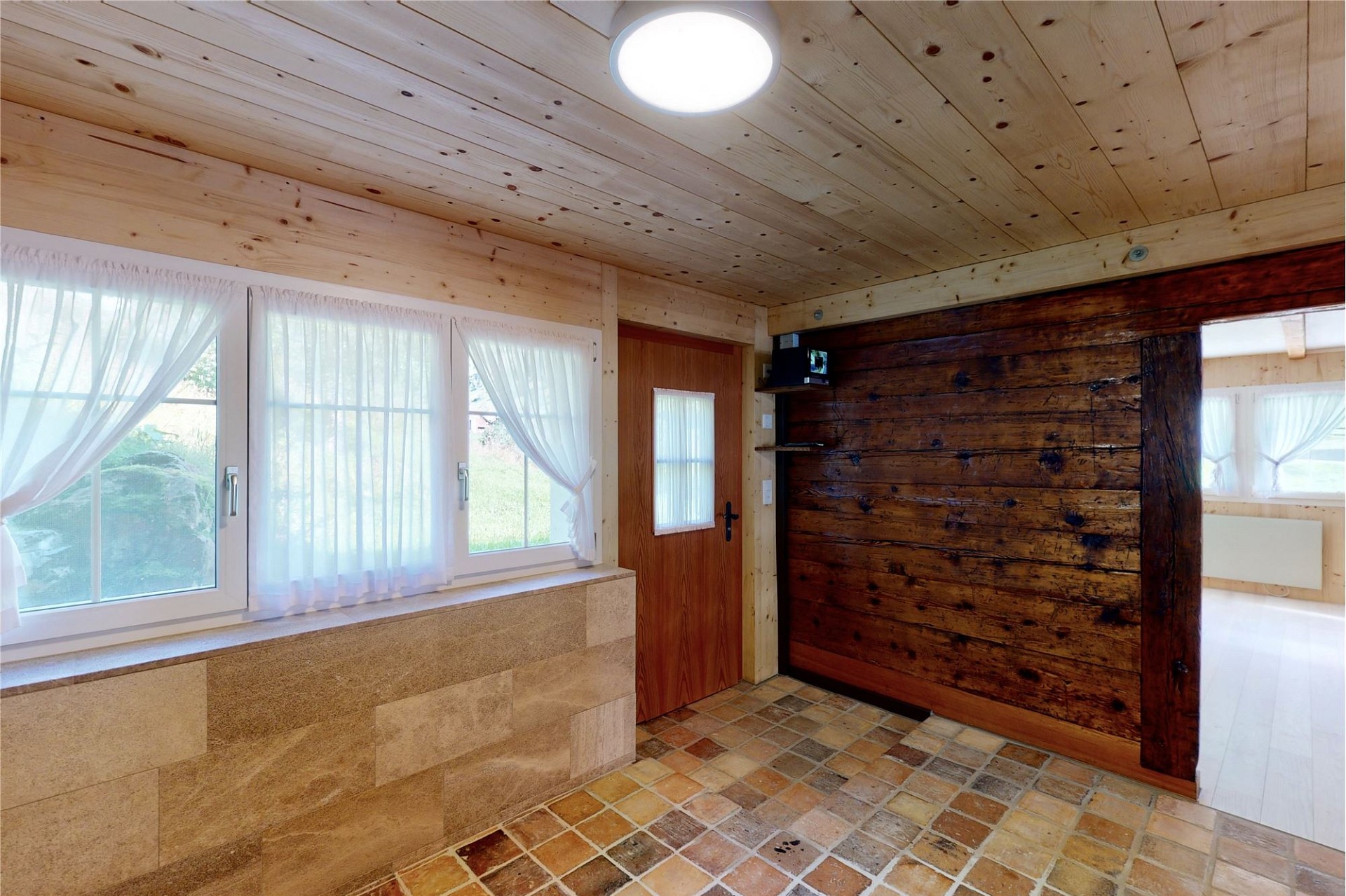 Heller Eingangsbereich mit Holzverkleidung und Natursteinboden