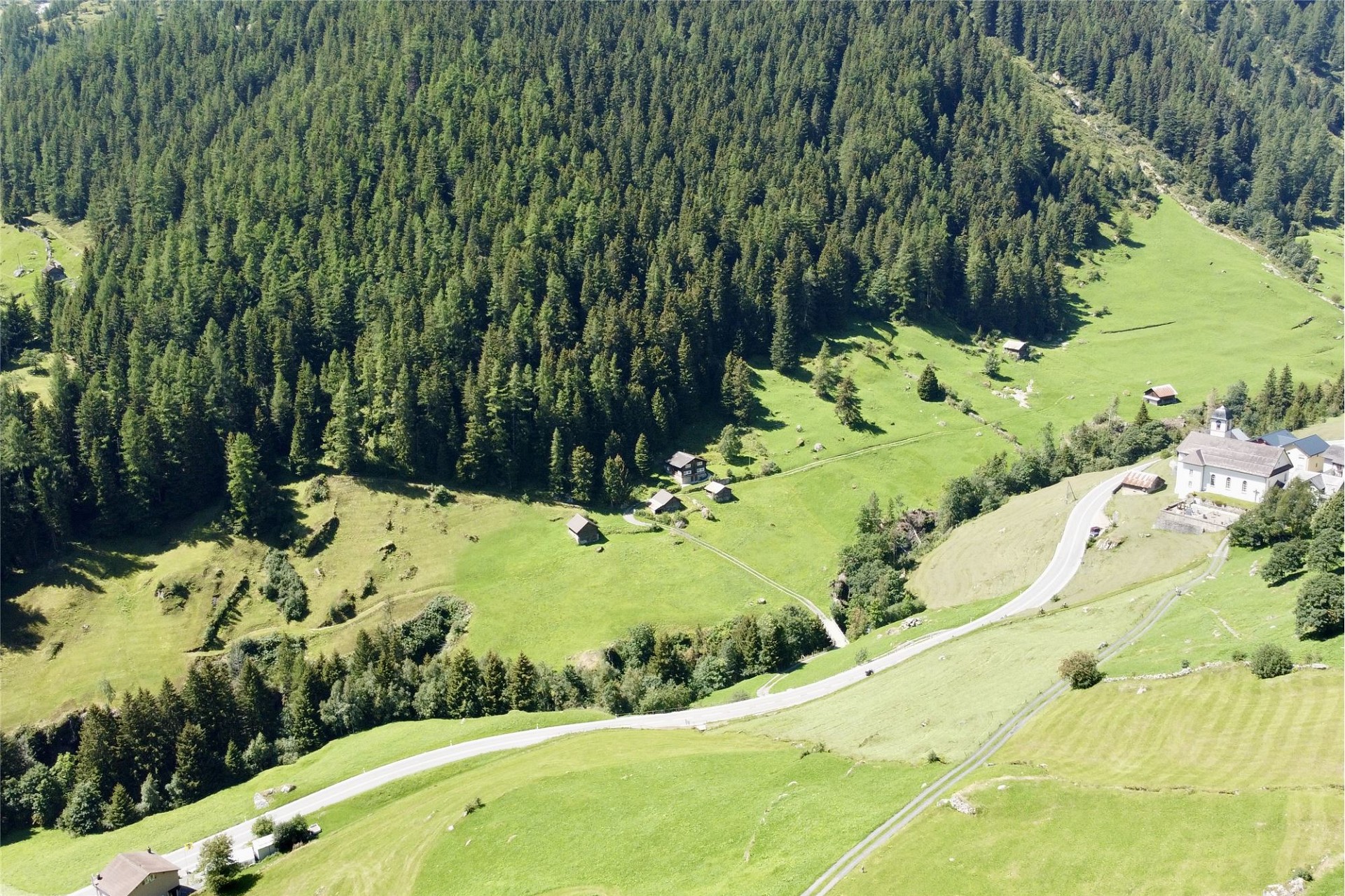 Alpine Tallandschaft mit Straße und verstreuten Gebäuden
