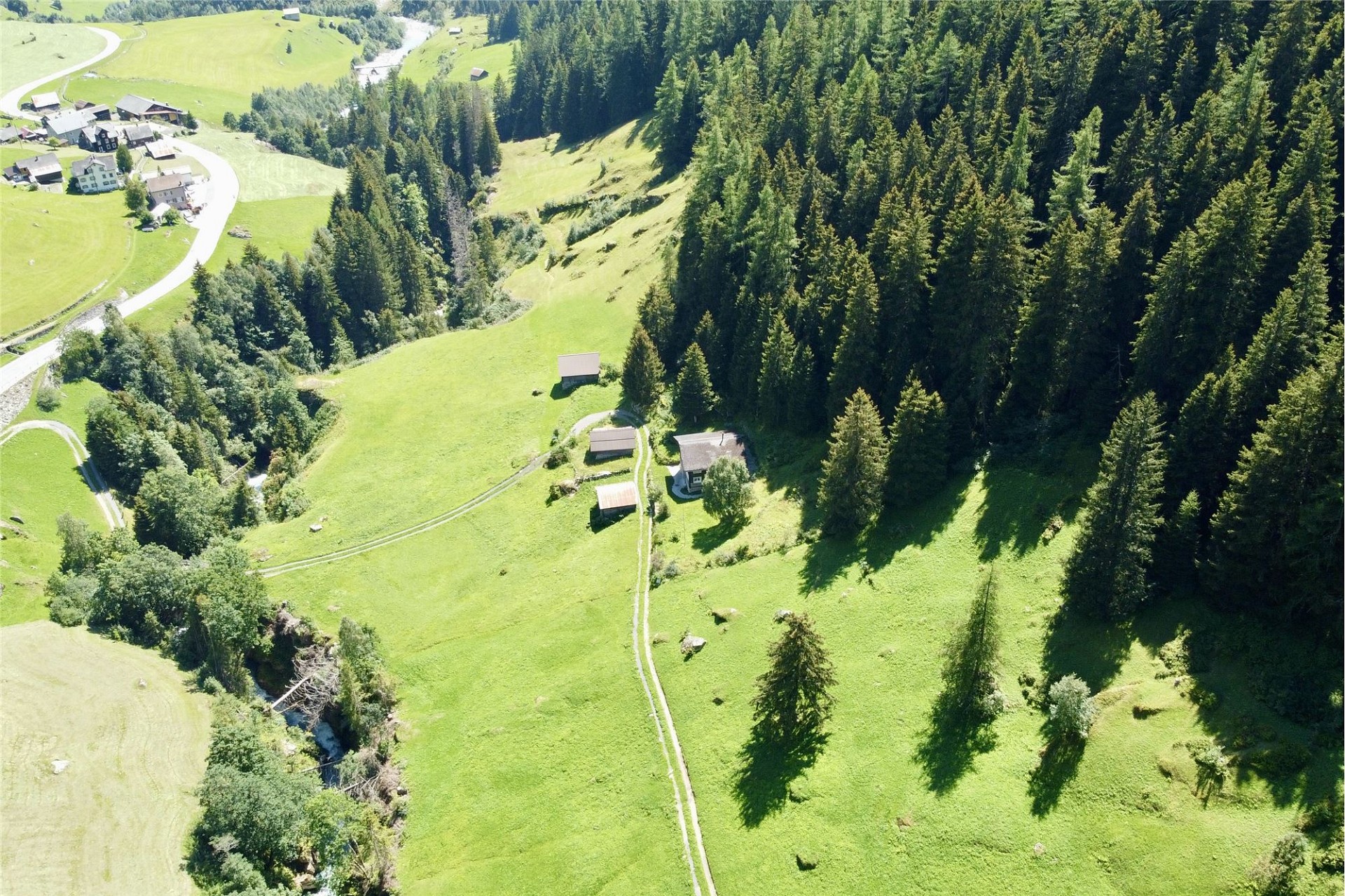 Luftaufnahme einer alpinen Landschaft mit verstreuten Gebäuden