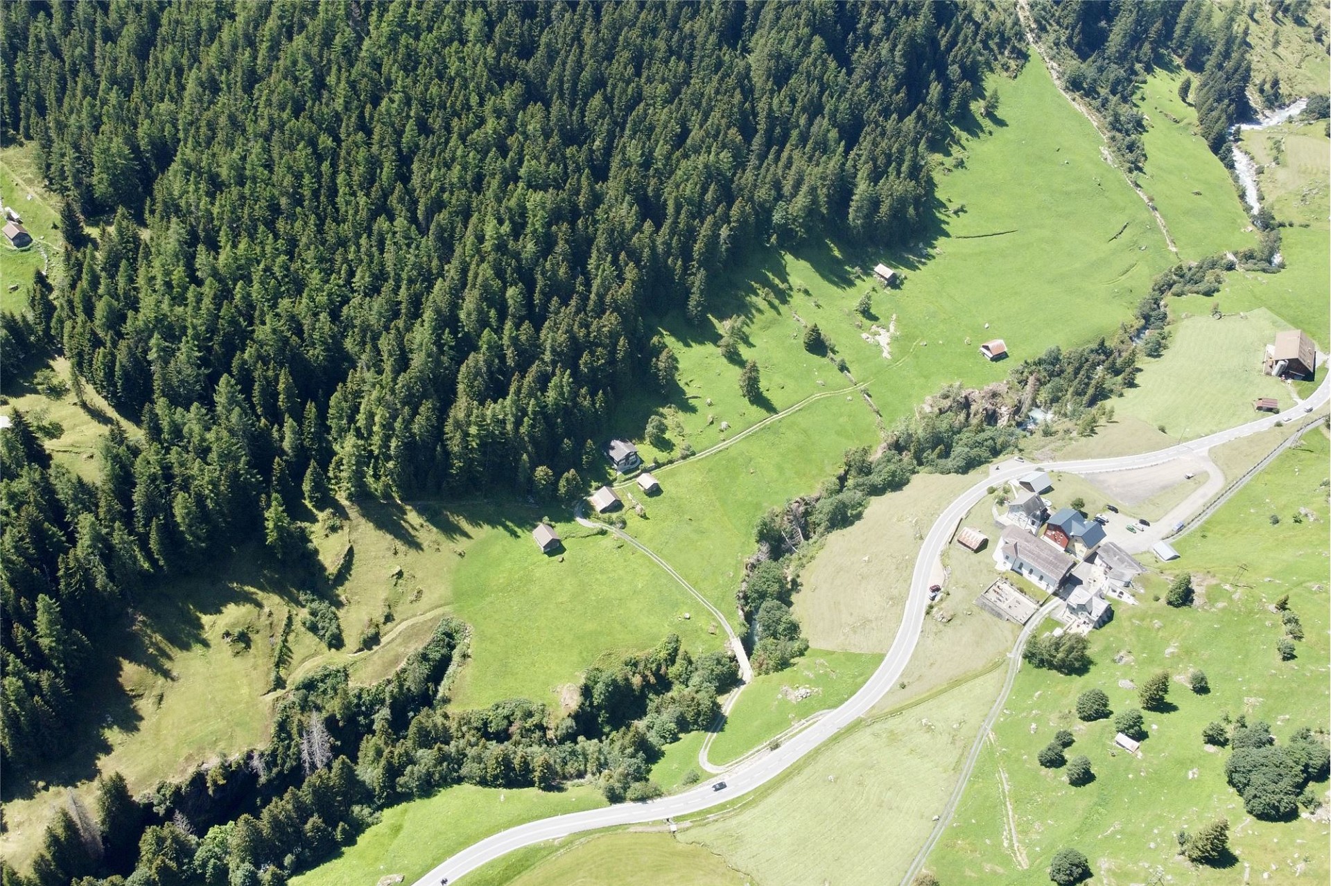 Luftaufnahme einer alpinen Landschaft mit einzelnen Gehöften