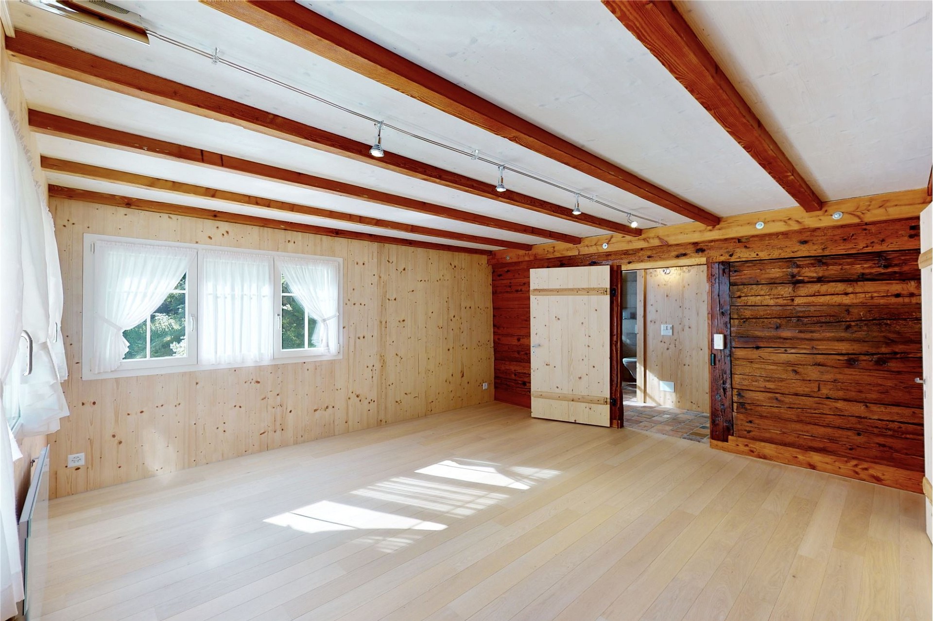 Heller, holzverkleideter Innenraum mit sichtbaren Deckenbalken