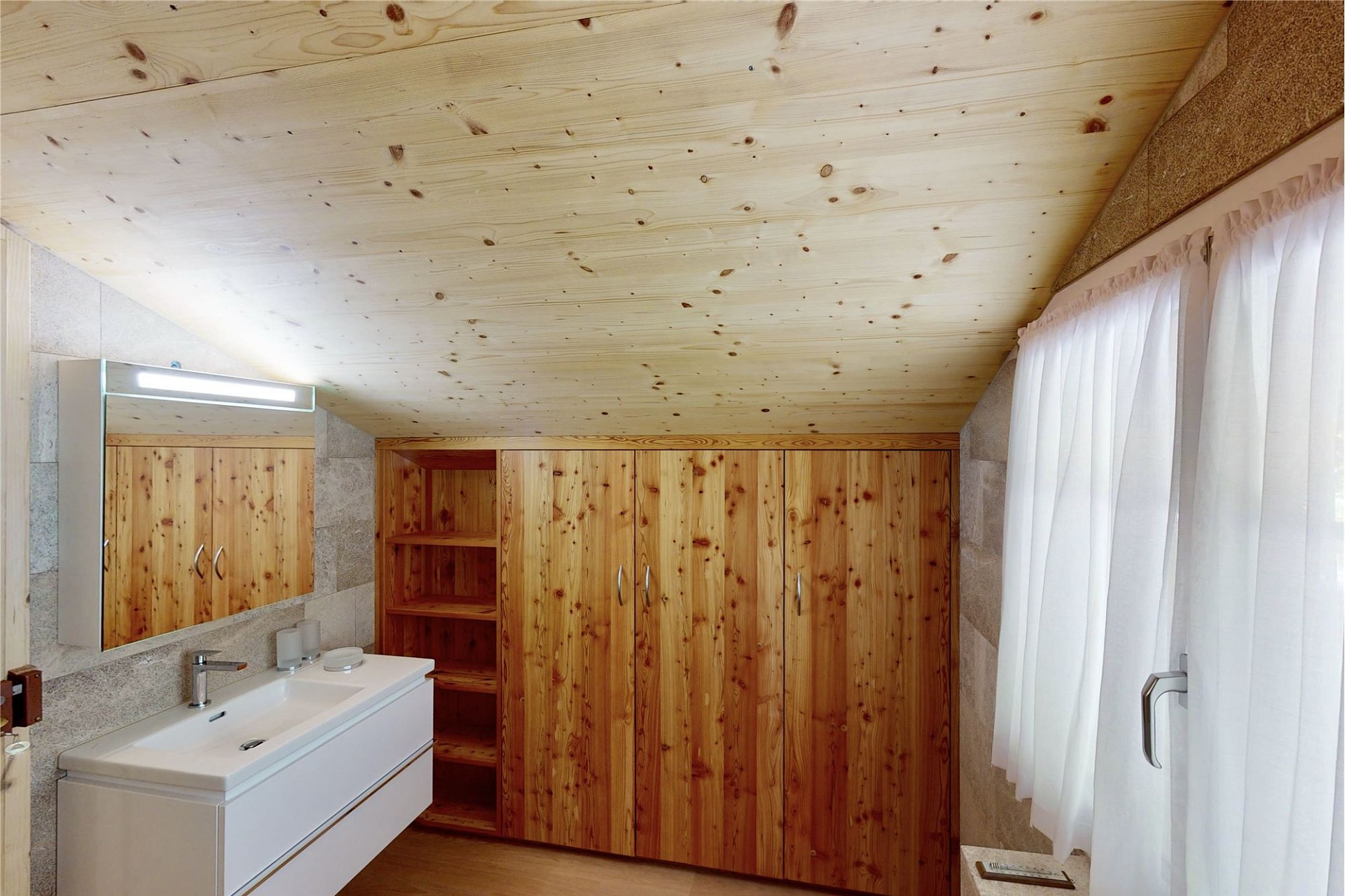 Badezimmer mit Holzschränken und Dachschräge