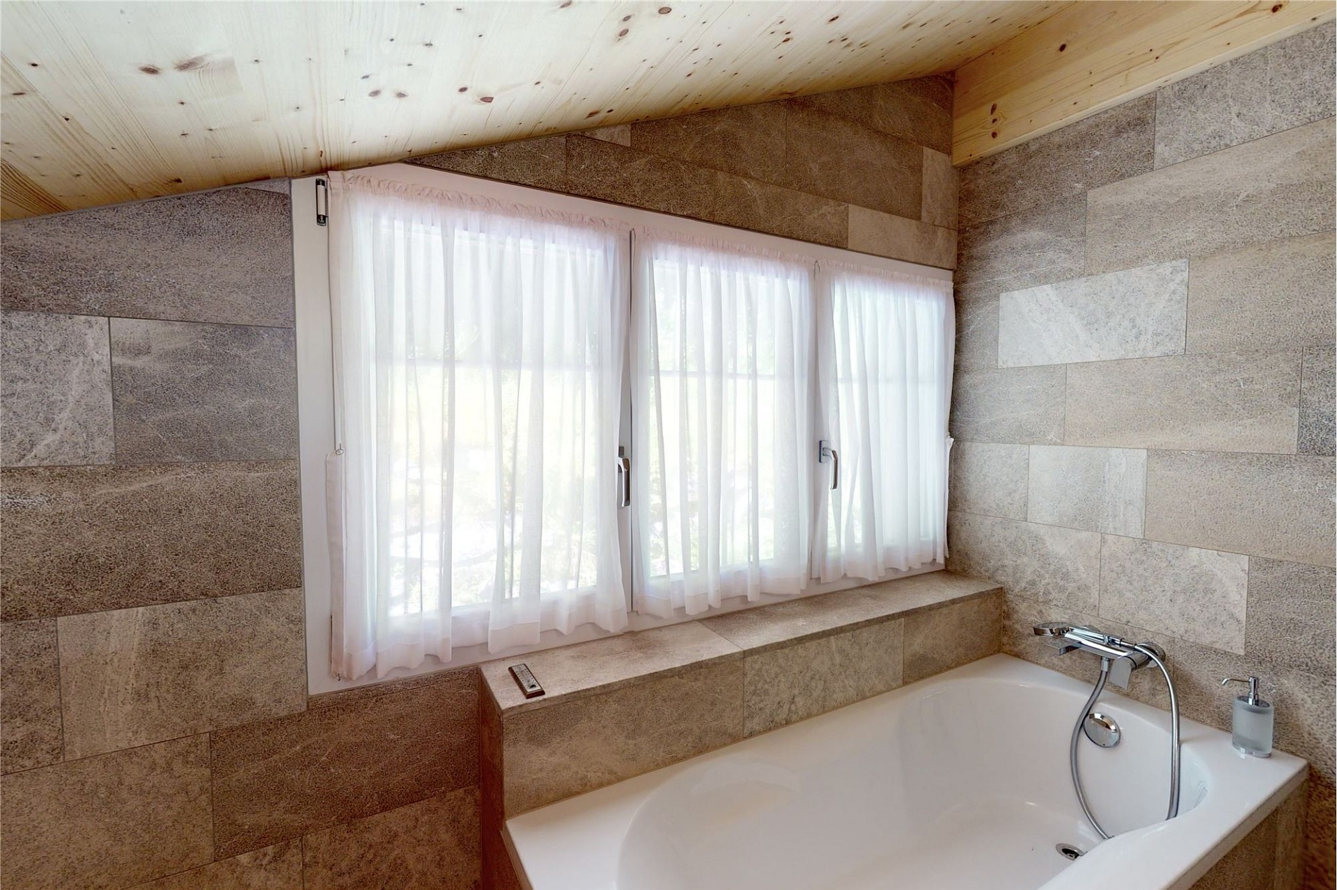 Helles Bad mit Natursteinverkleidung und Dachfenster