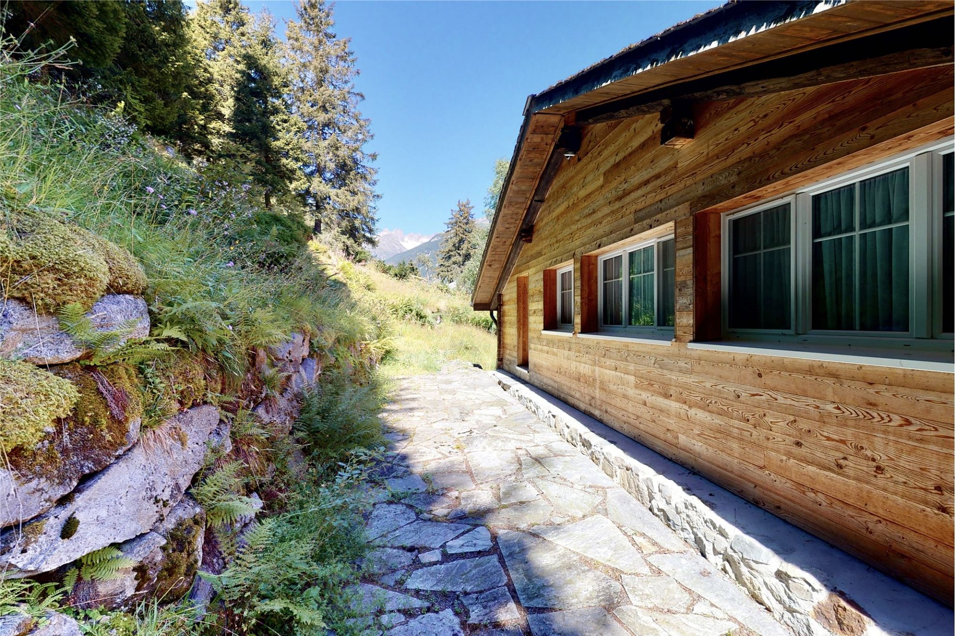 Alpenchalet mit Holzfassade und Natursteinweg