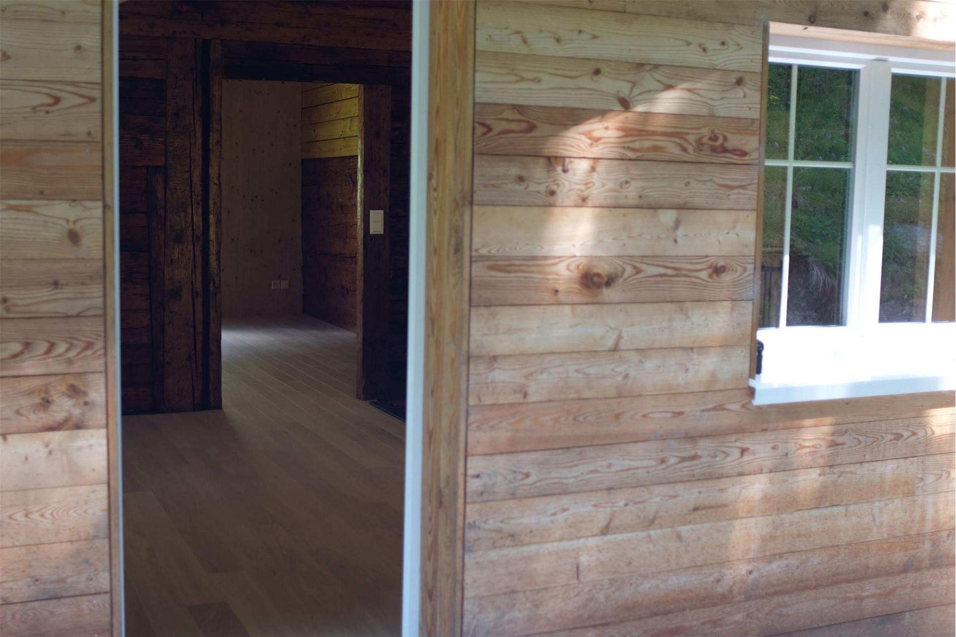 Holzverkleideter Innenraum mit Fenster und Durchgang