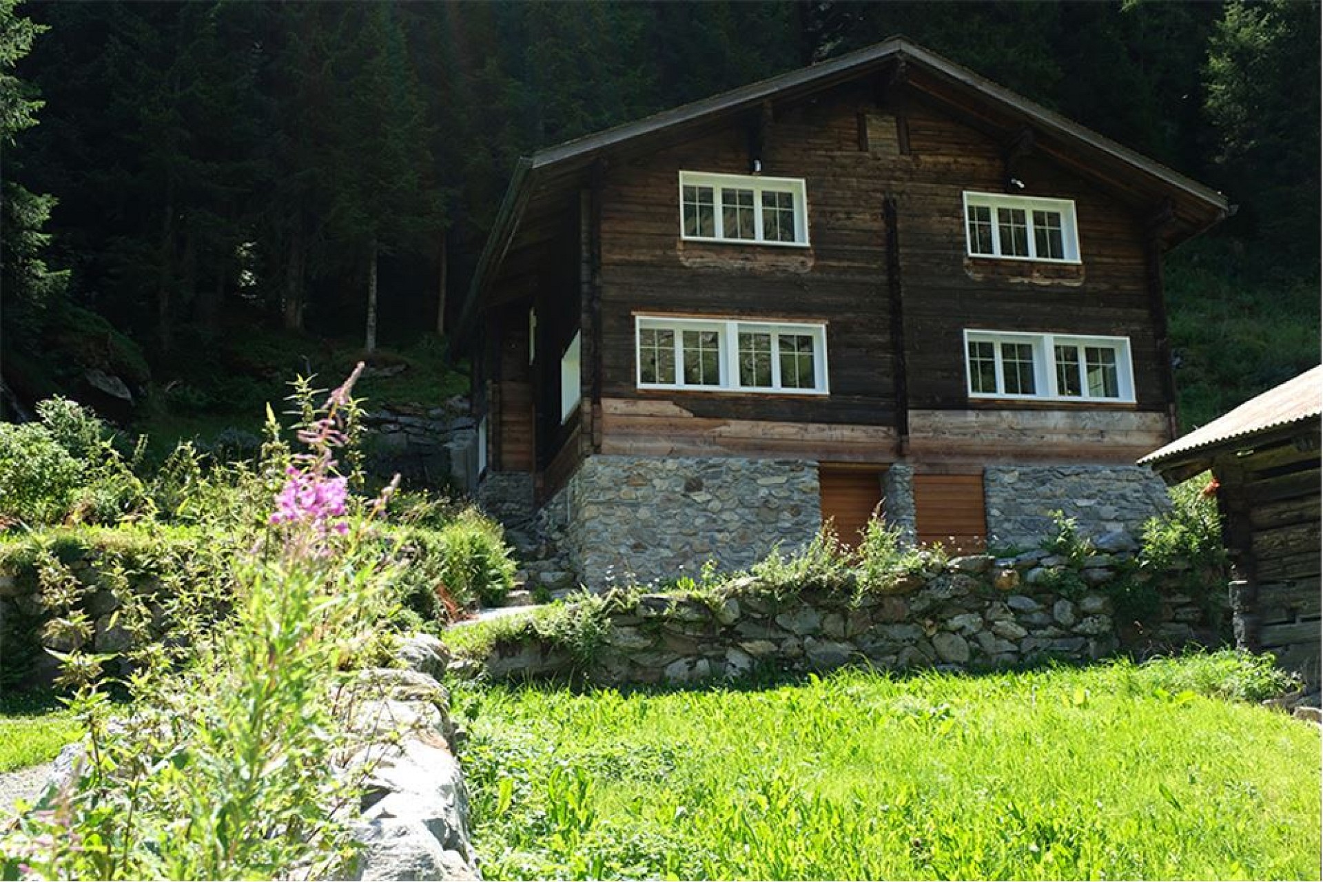 Berghaus mit Holzfassade und Steinsockel