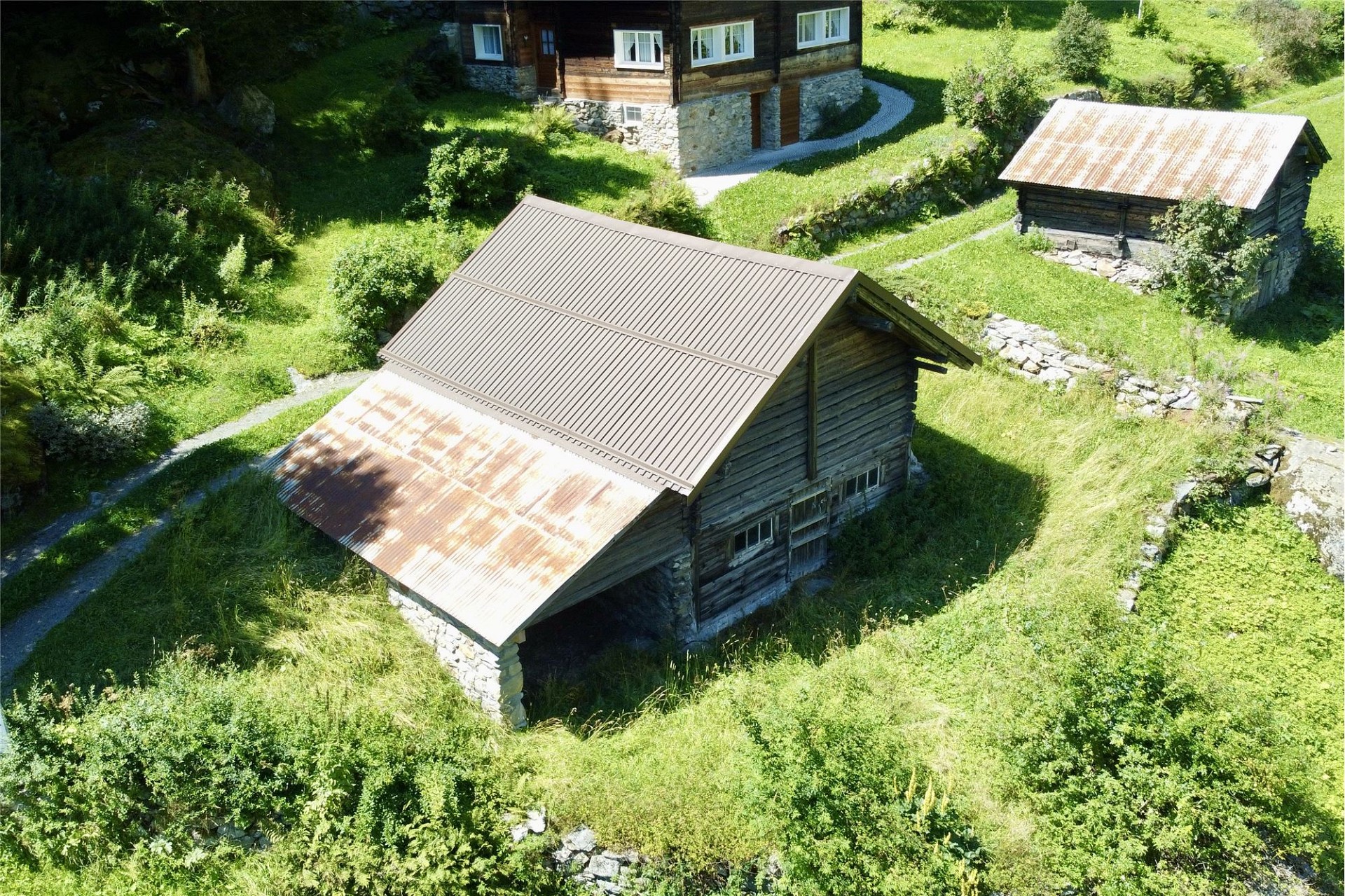 Alpenartige Nebengebäude in grüner Hanglage