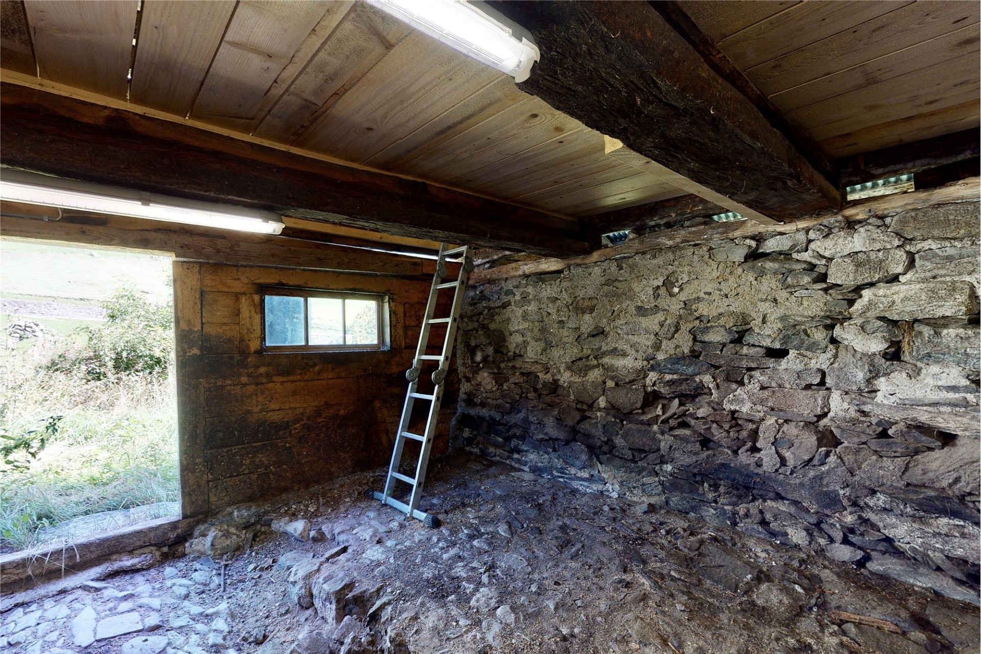 Rustikaler Innenraum mit Steinmauern und Leiter