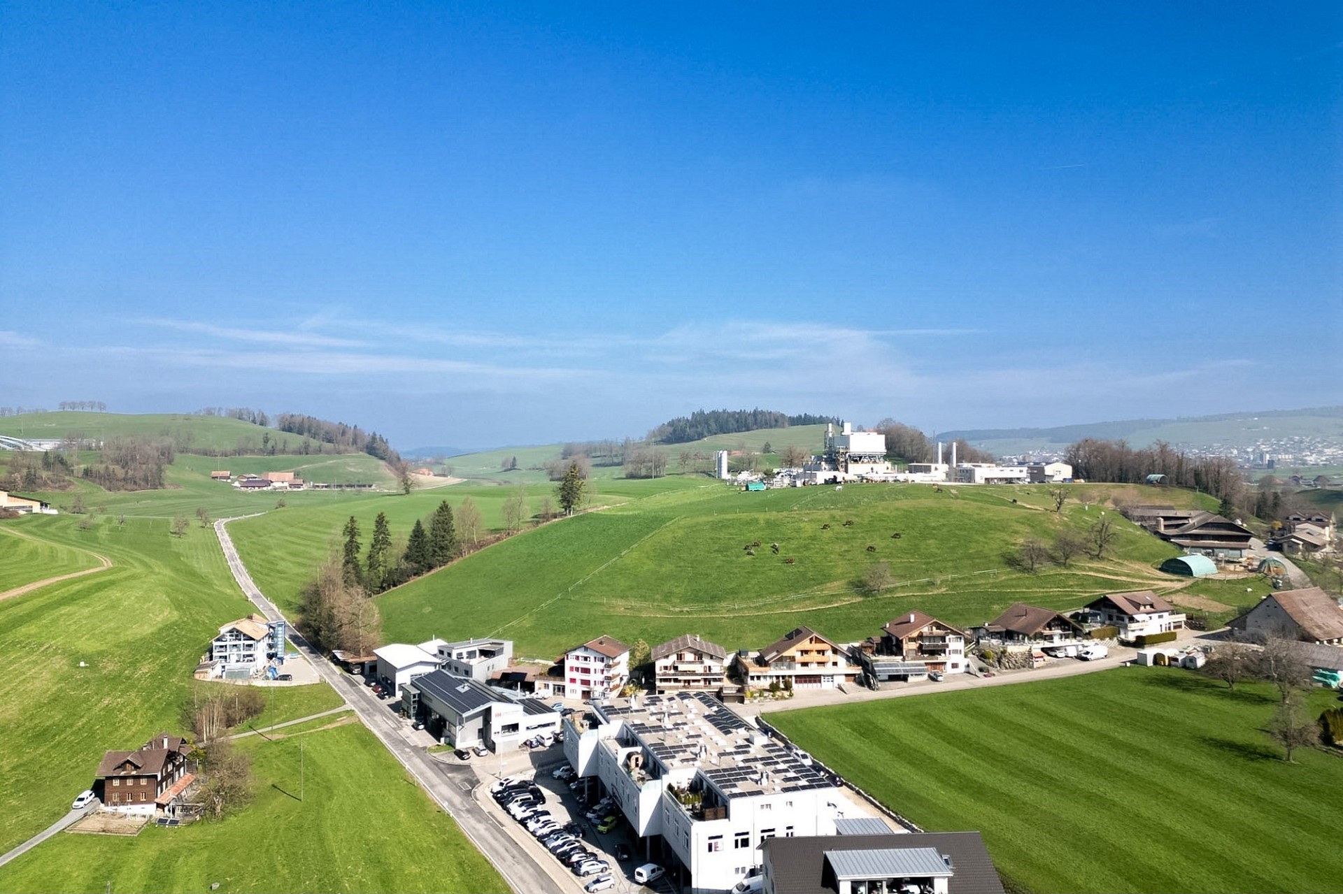 Luftaufnahme einer grünen Hügellandschaft mit Gebäuden