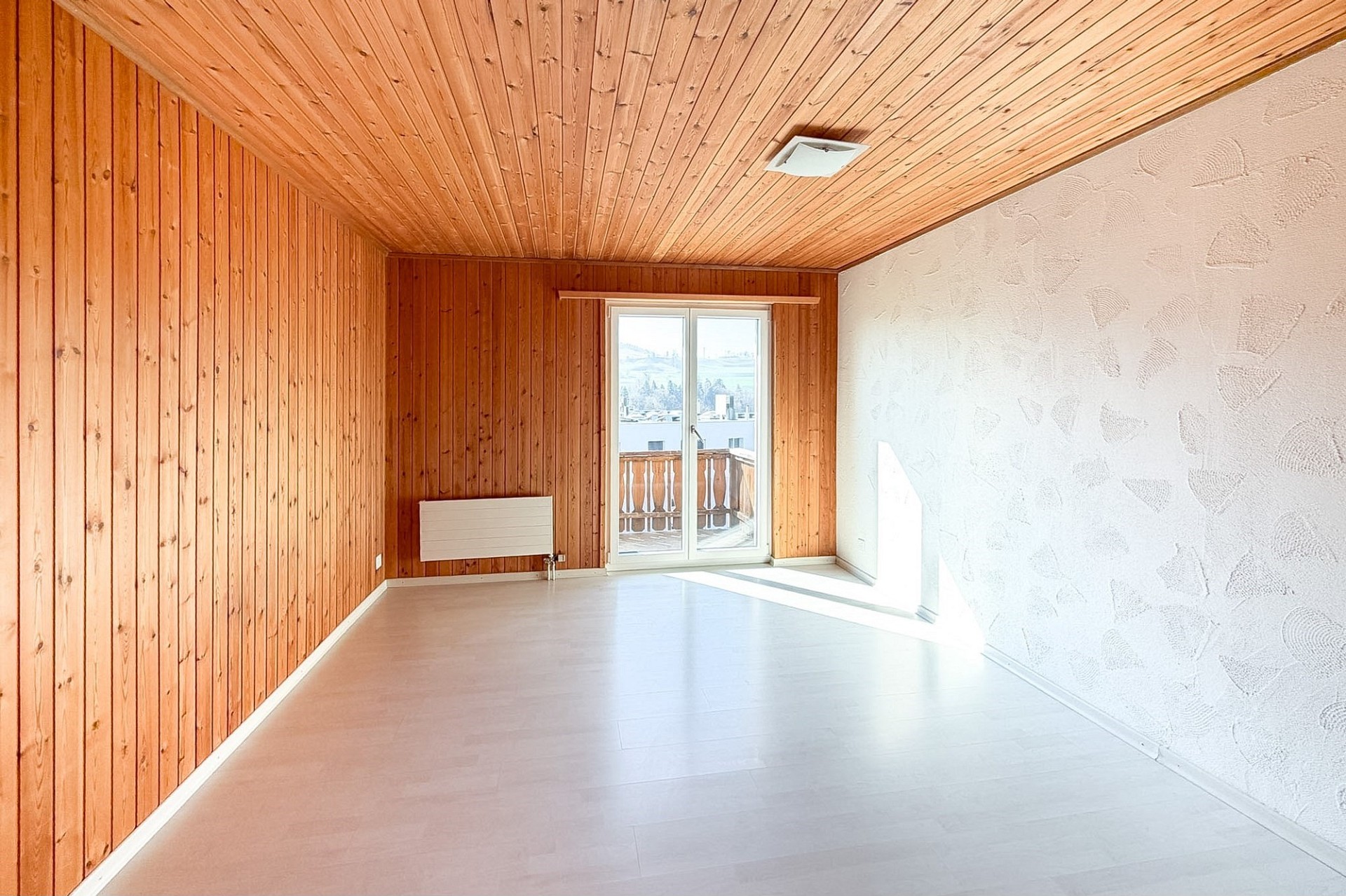 Leerer Raum mit Holzverkleidung und Balkonzugang