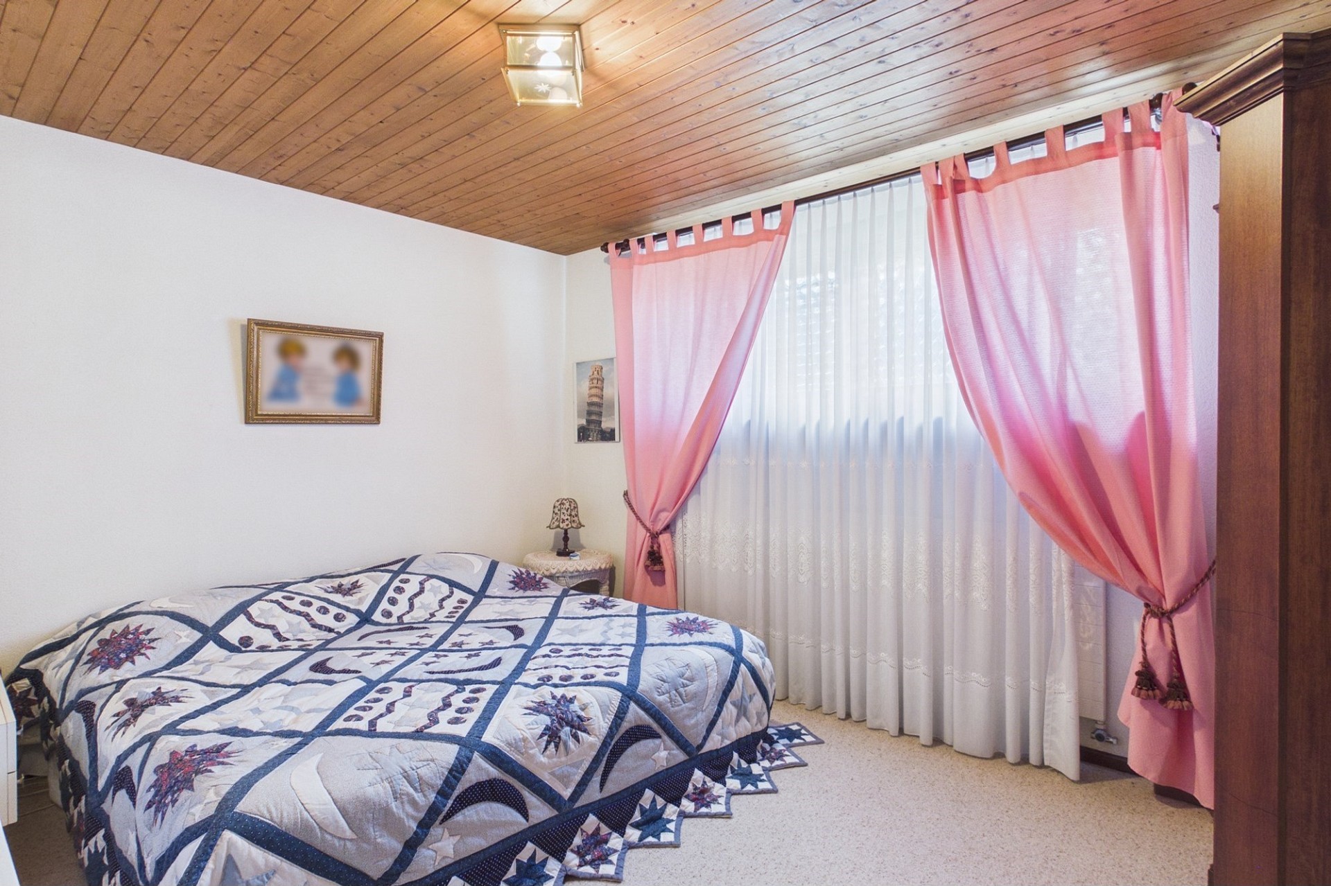 Schlafzimmer mit Holzdecke und rosafarbenen Vorhängen