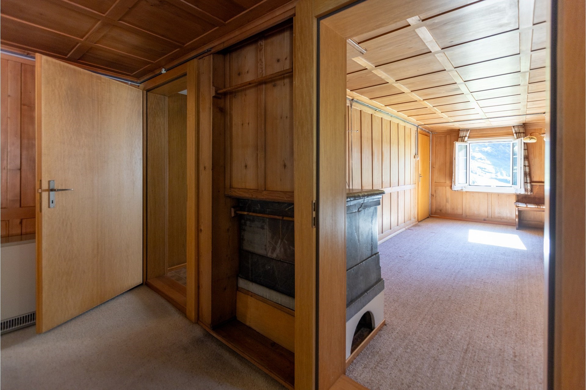 Holzvertäfelter Innenraum mit Kamin und Teppichboden
