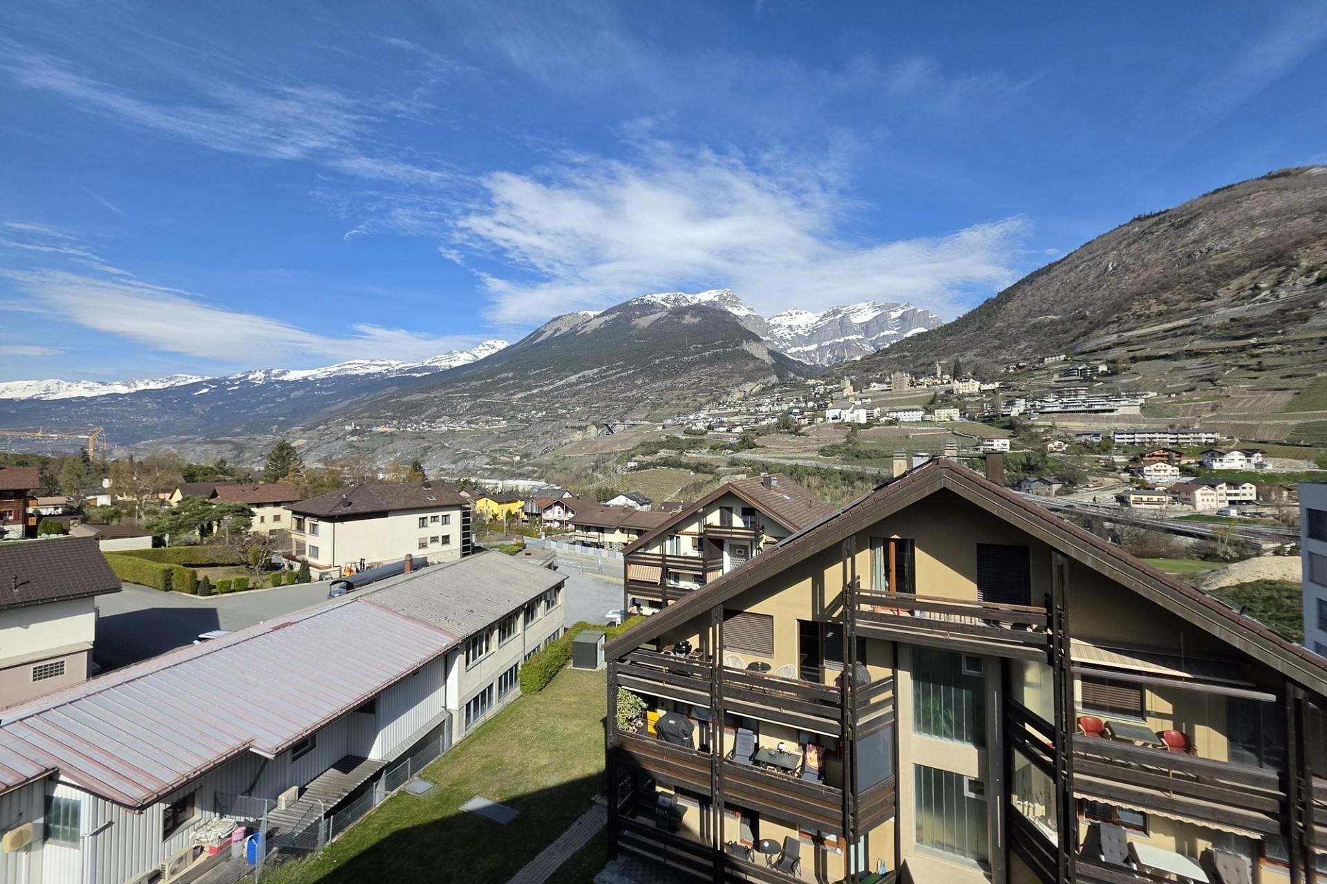 Bergblick über Wohnhäuser und Alpenpanorama