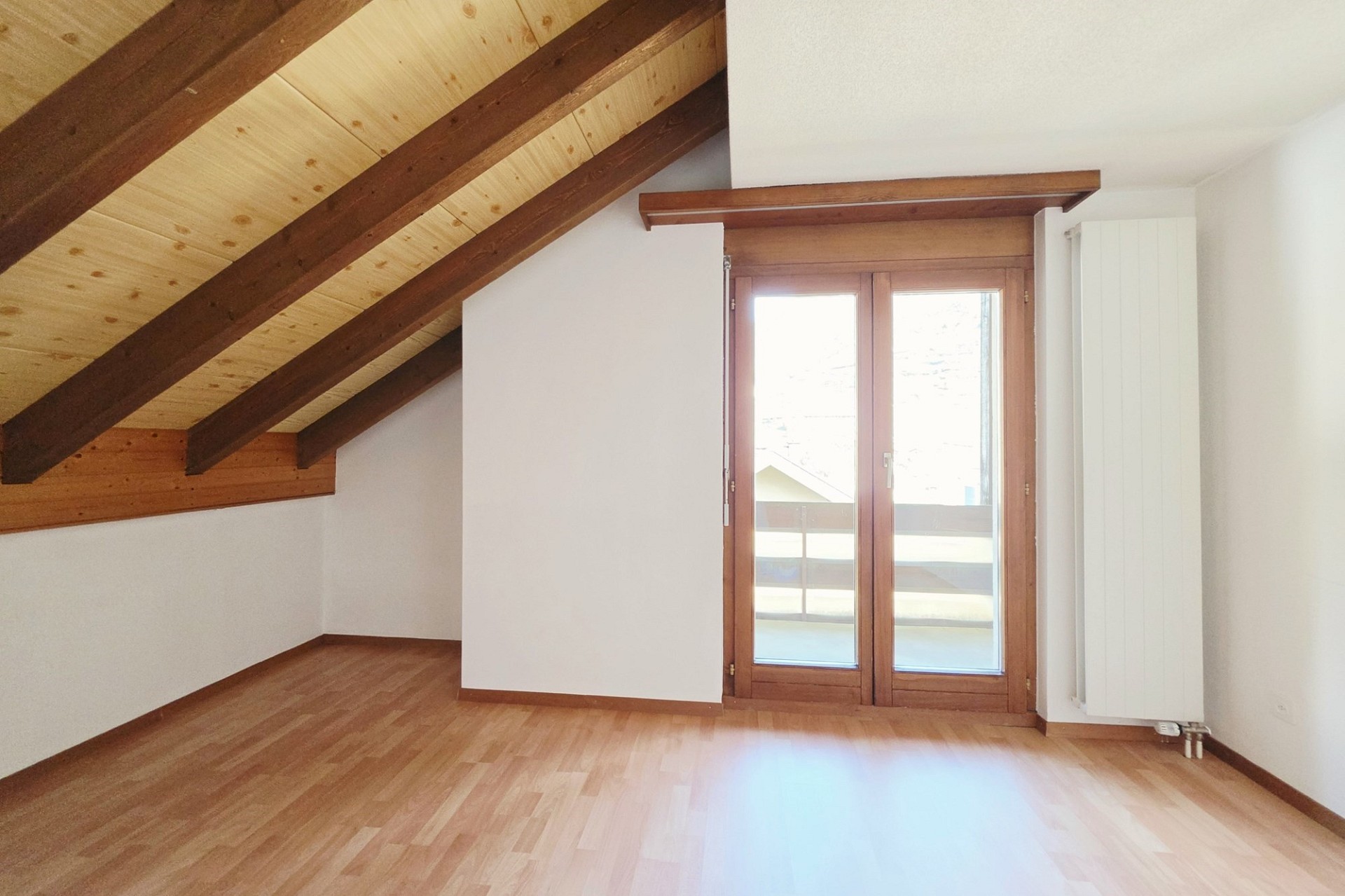 Dachzimmer mit Holzbalken und Balkonzugang