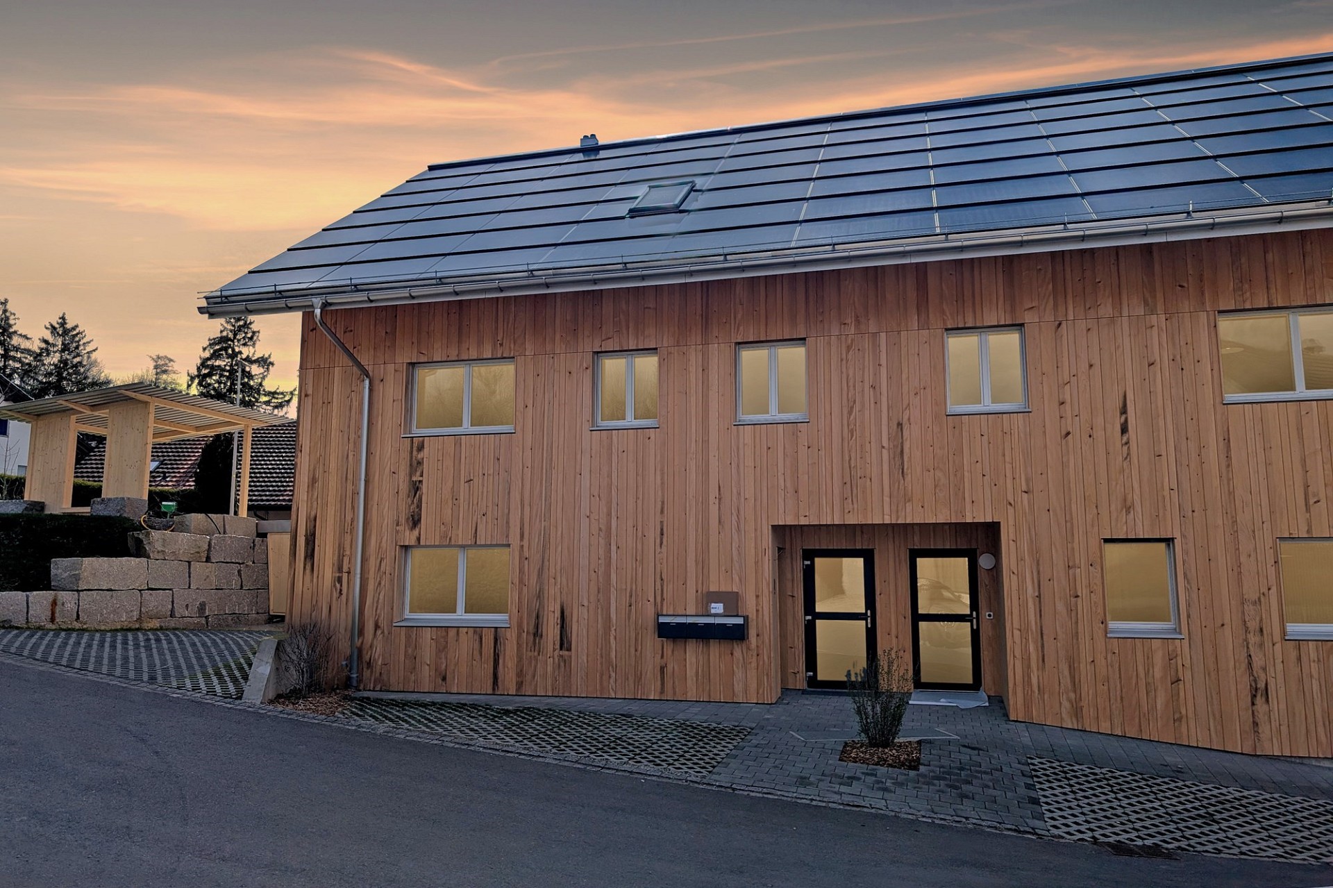 Moderne Holzfassade mit Solardach bei Abendlicht