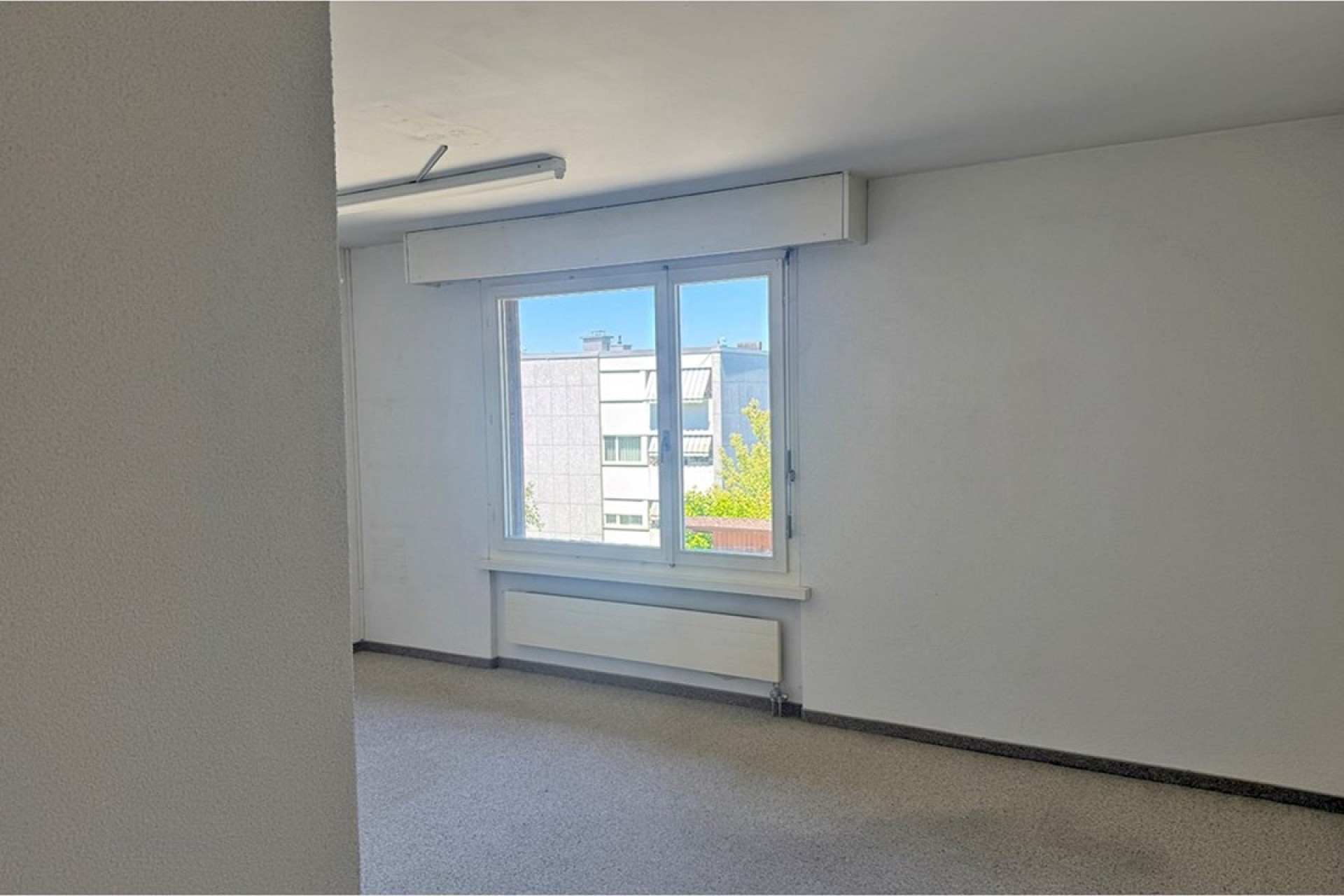 Leerer Wohnraum mit Fenster und Heizkörper