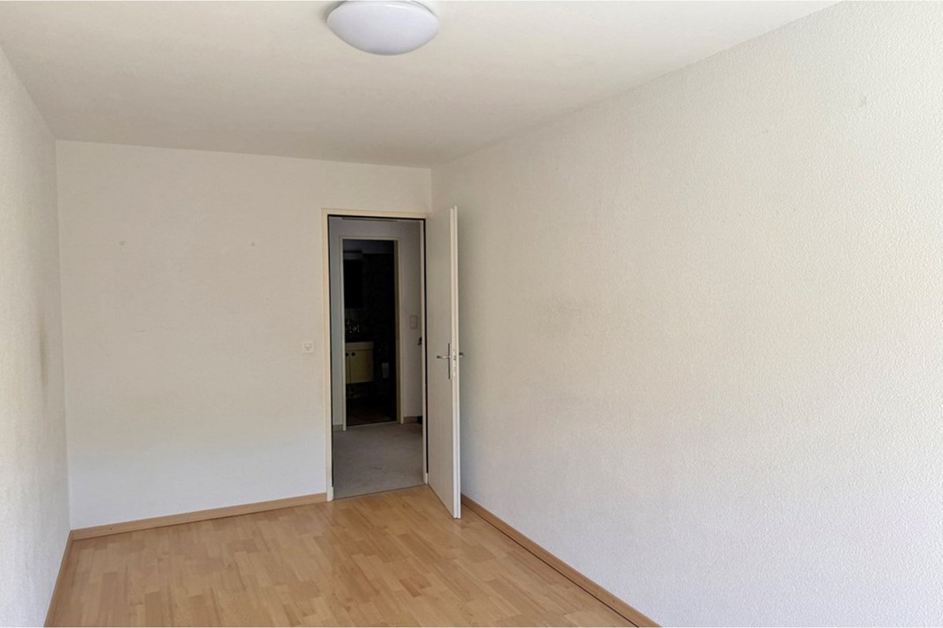 Leeres, helles Zimmer mit Holzboden