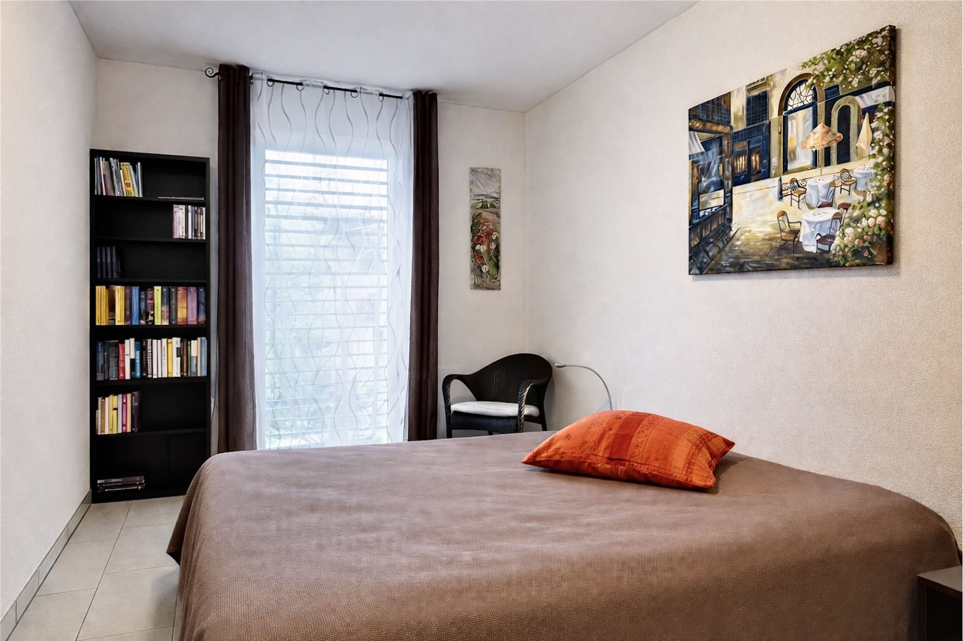 Helles Schlafzimmer mit Bett, Bücherregal und Fenster