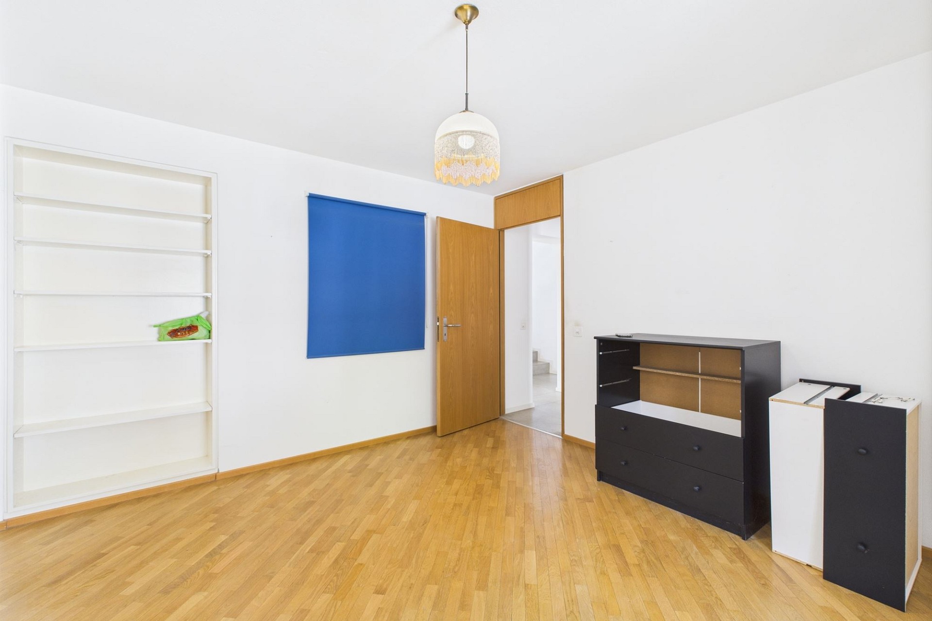 Helles, weitgehend leeres Schlafzimmer mit Parkettboden