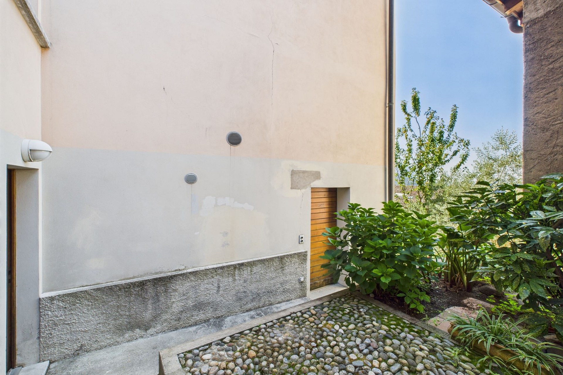 Außenhof mit Putzfassade und Gartenbereich