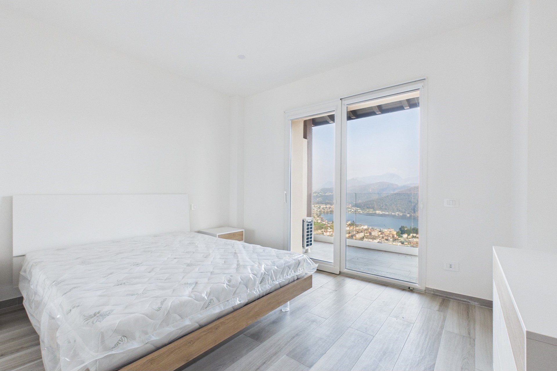 Helles Schlafzimmer mit Balkon- und Seeblick