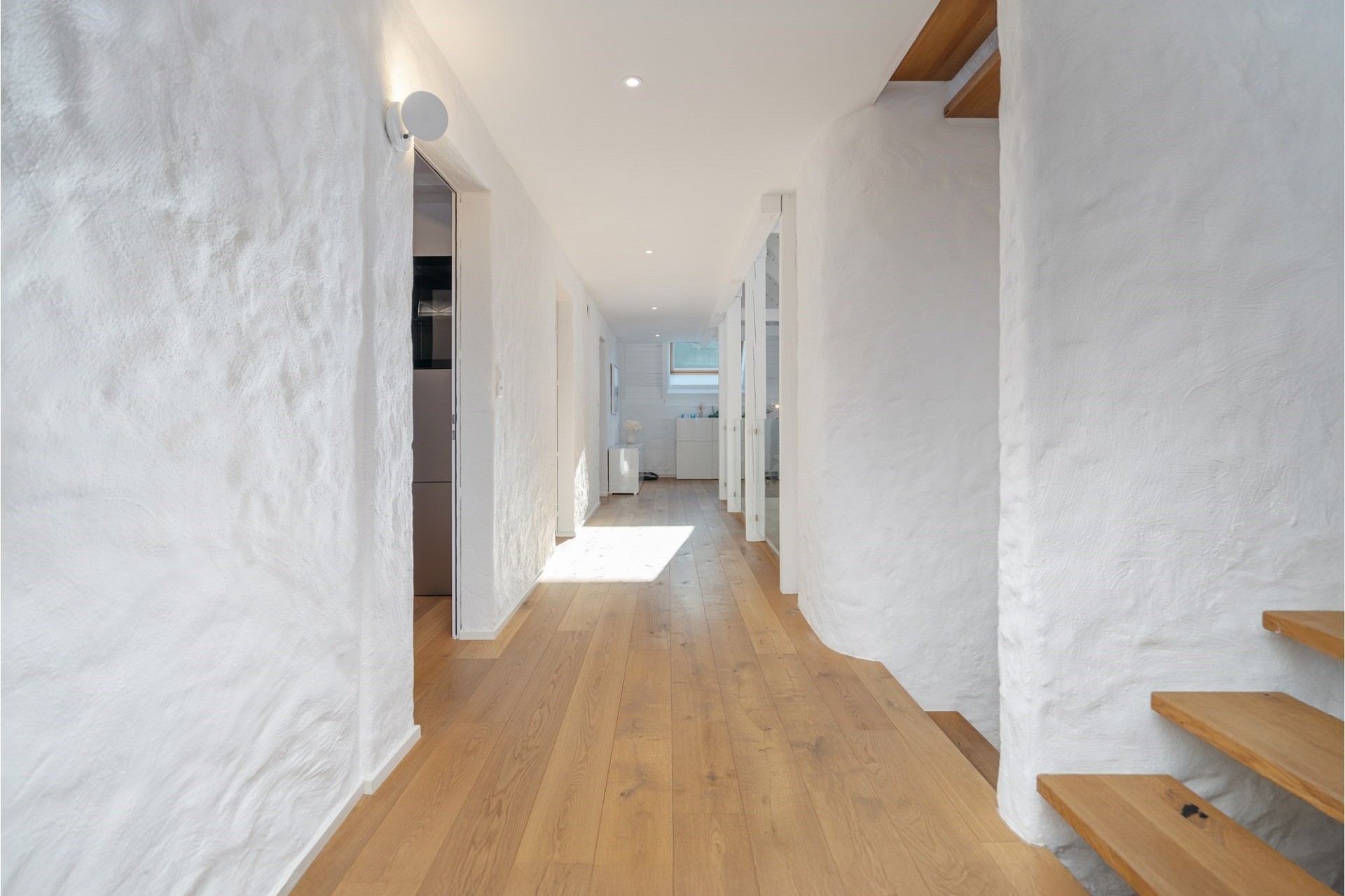 Heller Flur mit Holzfußboden und weißen Wänden