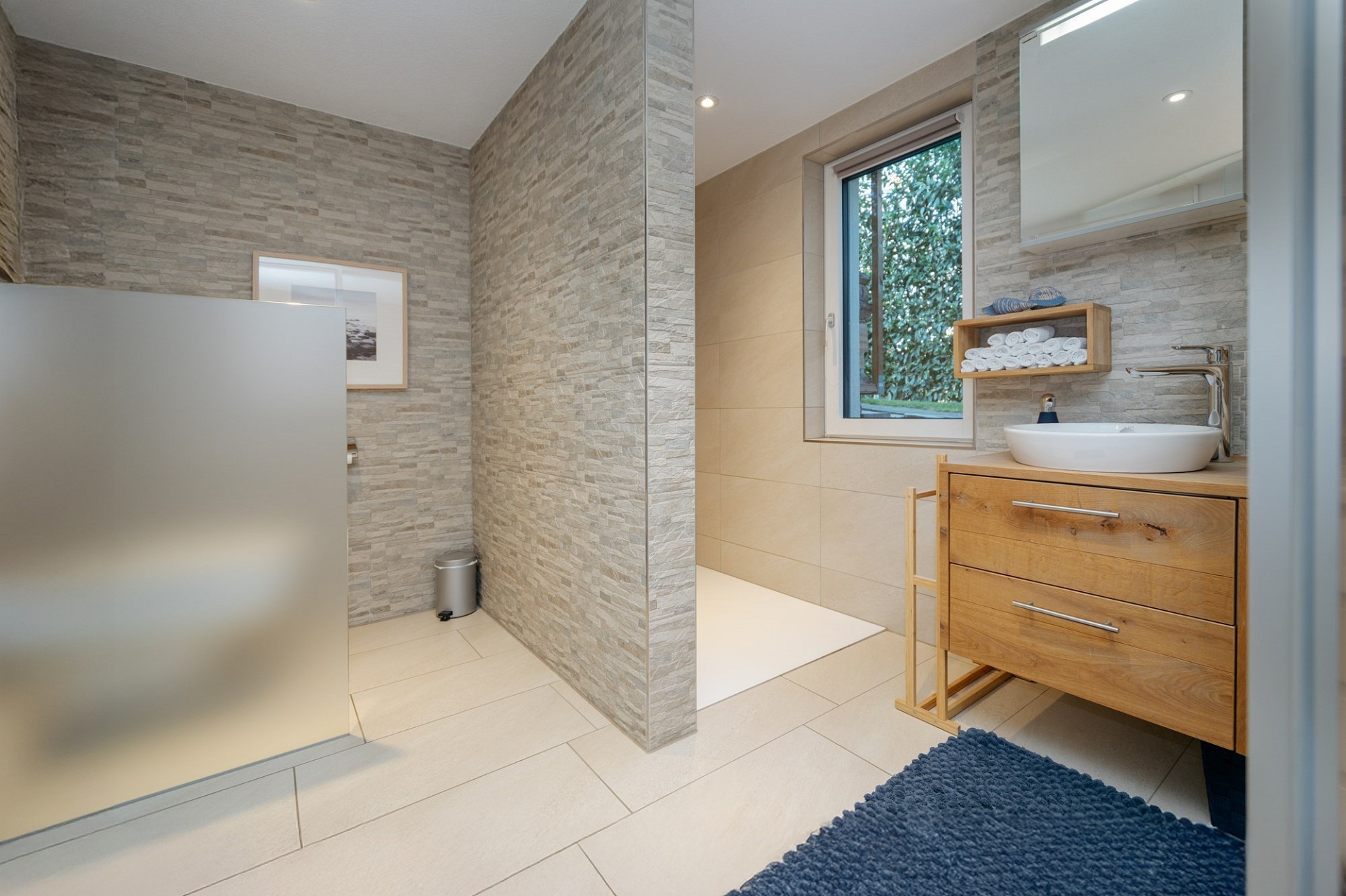 Modernes Badezimmer mit Steinoptik und Holzmöbeln