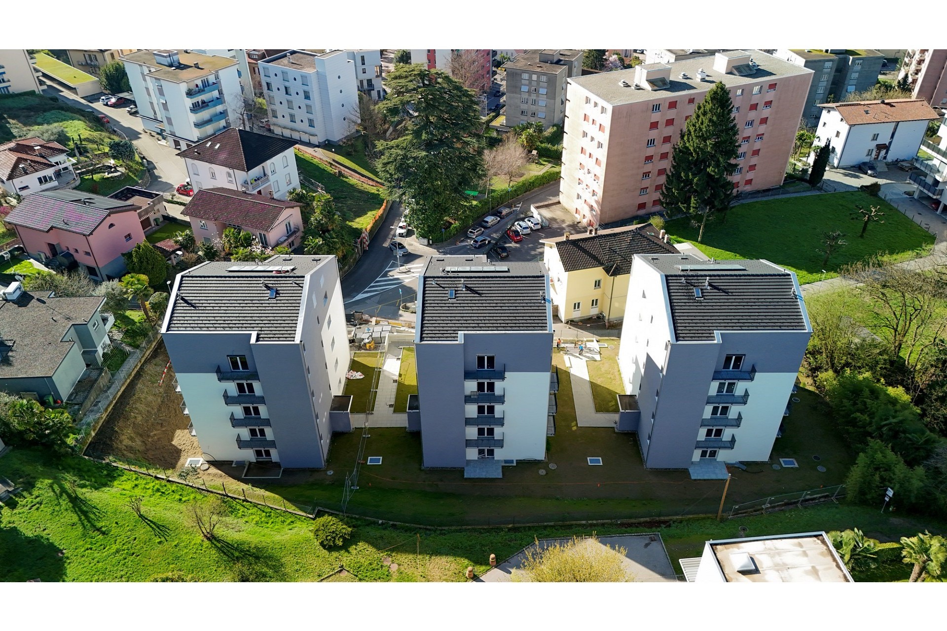 Luftaufnahme eines Wohnquartiers mit drei neuen Mehrfamilienhäusern