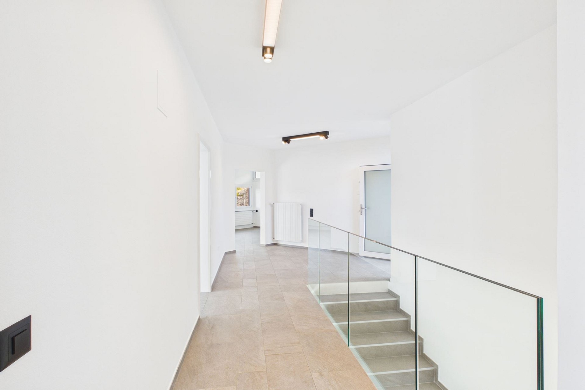 Heller Flur mit Treppe und Glasgeländer