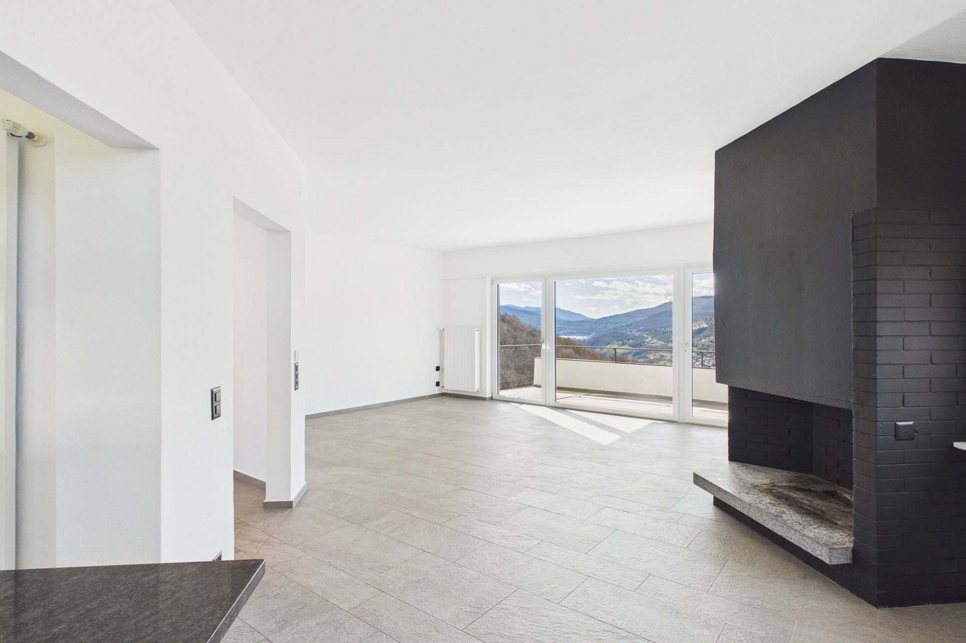 Heller, leerer Wohnraum mit Kamin und Bergblick