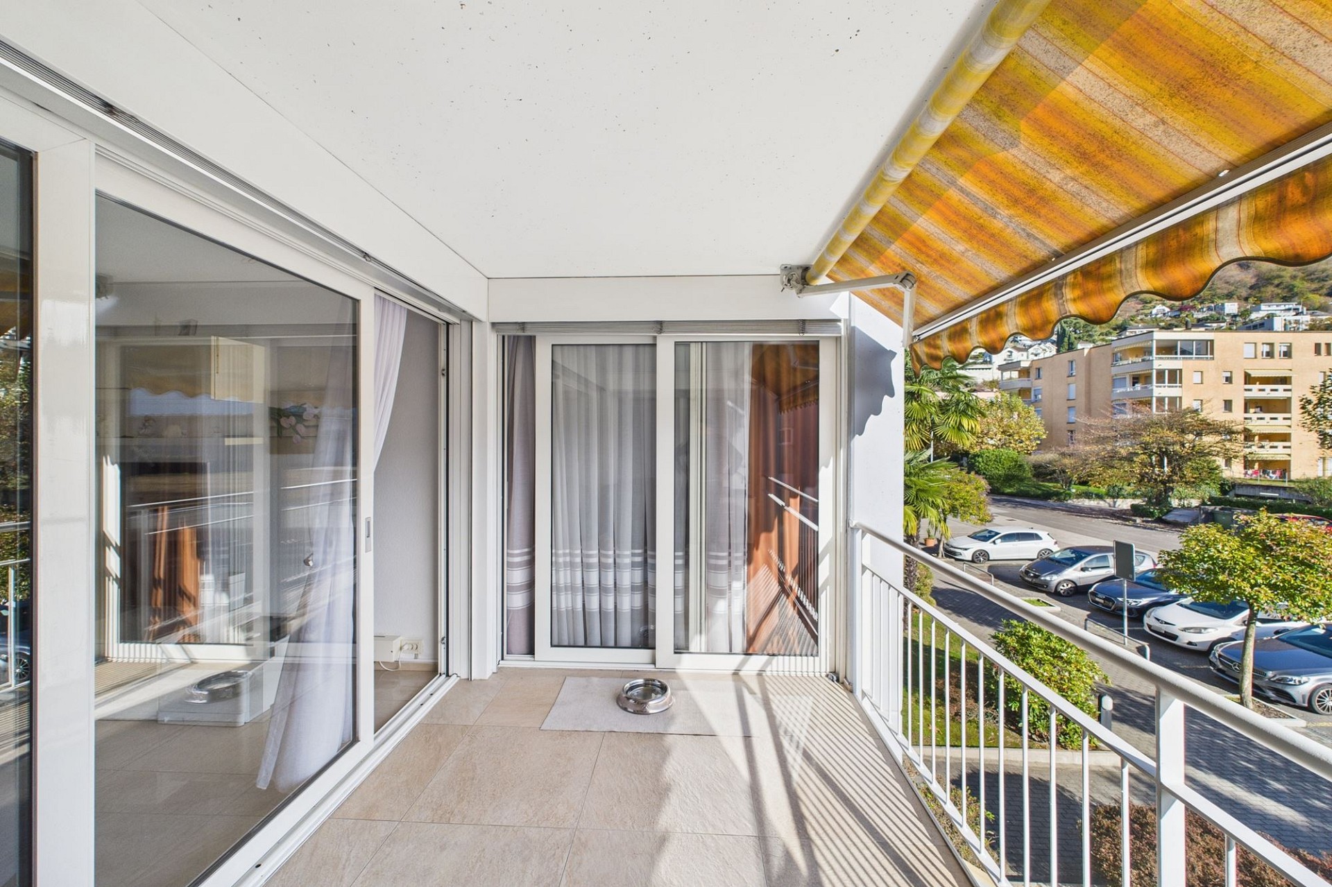 Überdachter Balkon mit Markise und Blick ins Wohnumfeld
