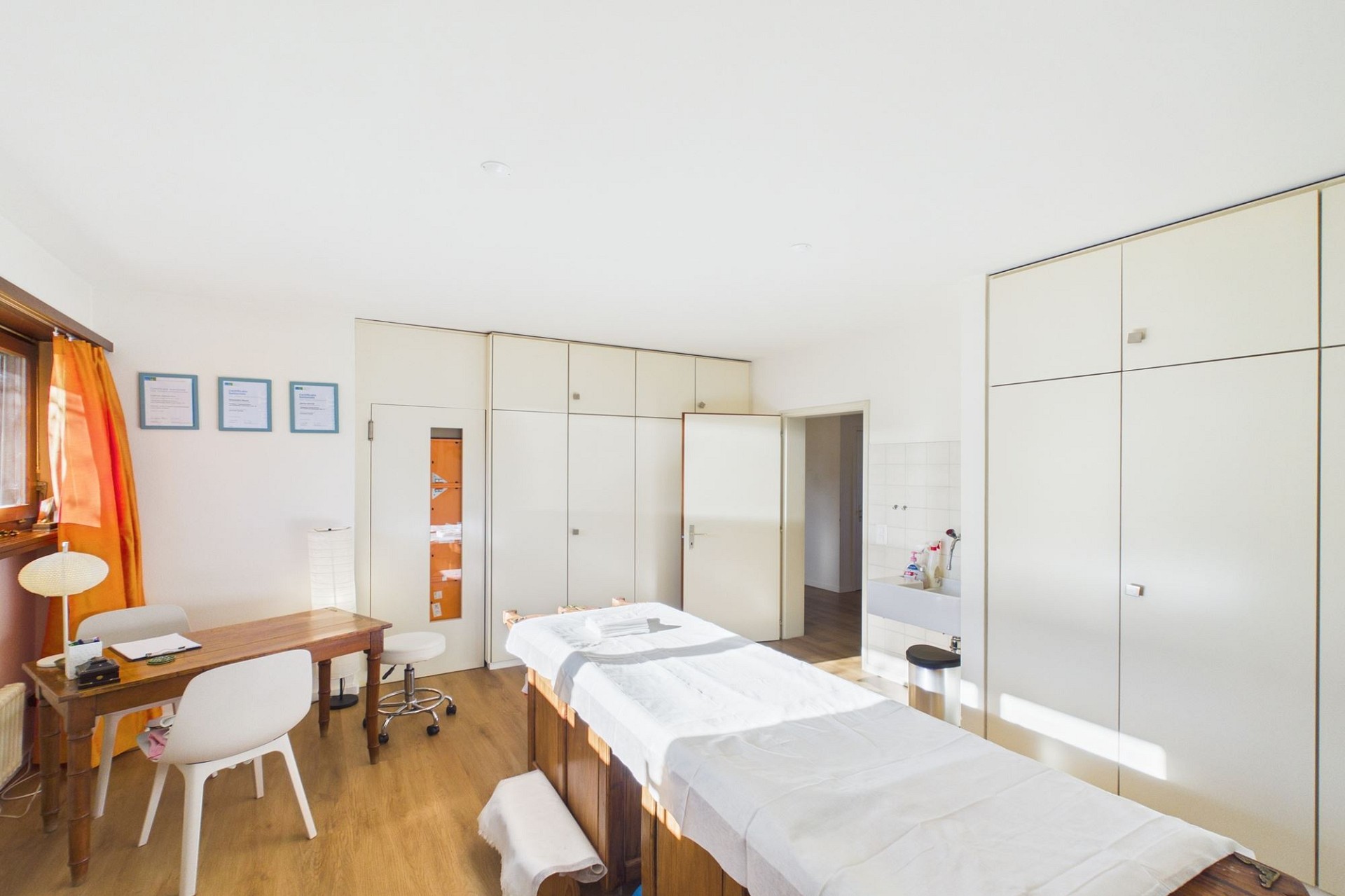Behandlungsraum mit Bett und Schränken