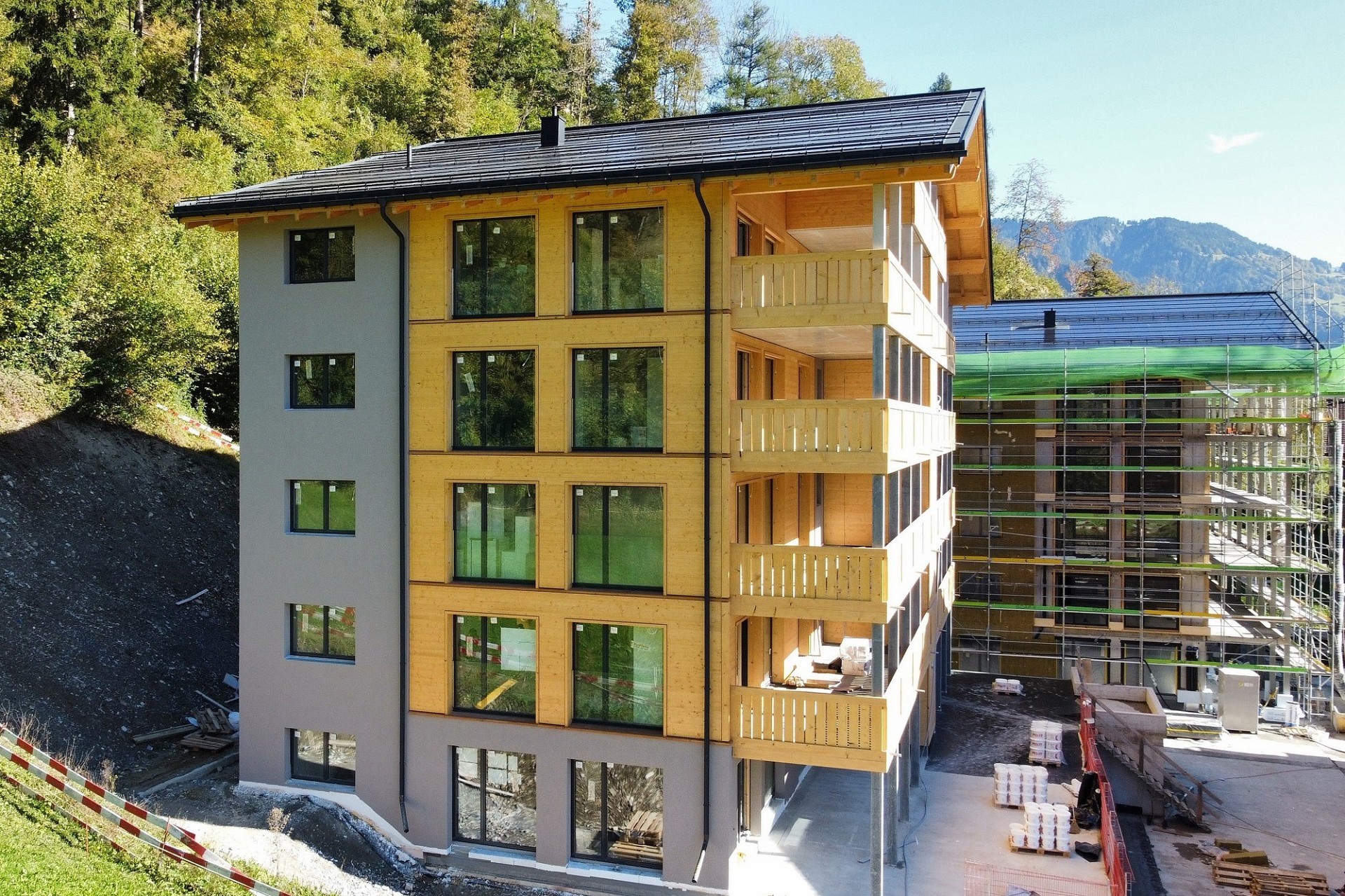 Mehrfamilienhaus im Bau mit Holzfassade und Balkonen