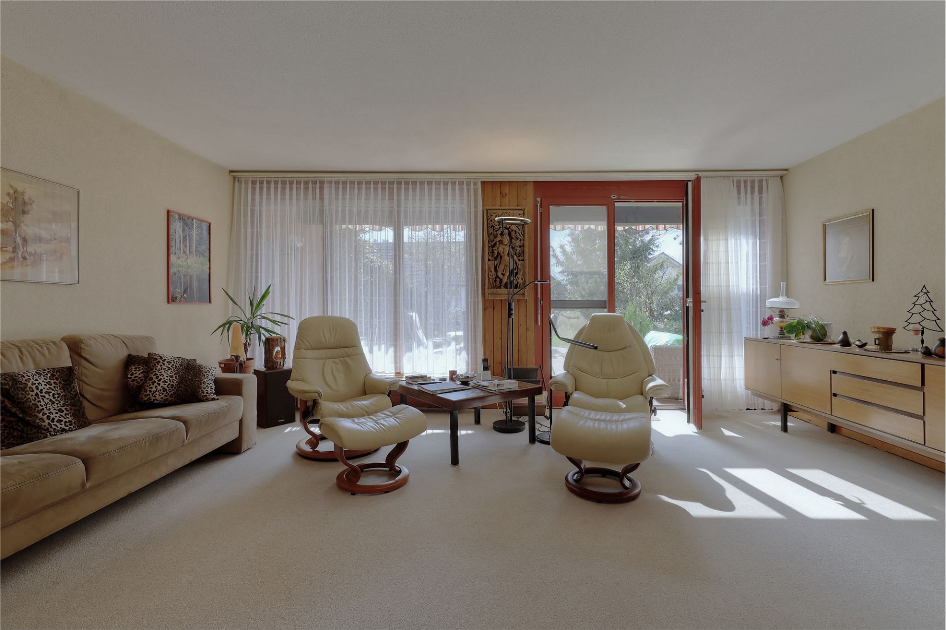 Helles Wohnzimmer mit Sitzgruppe und Balkonzugang