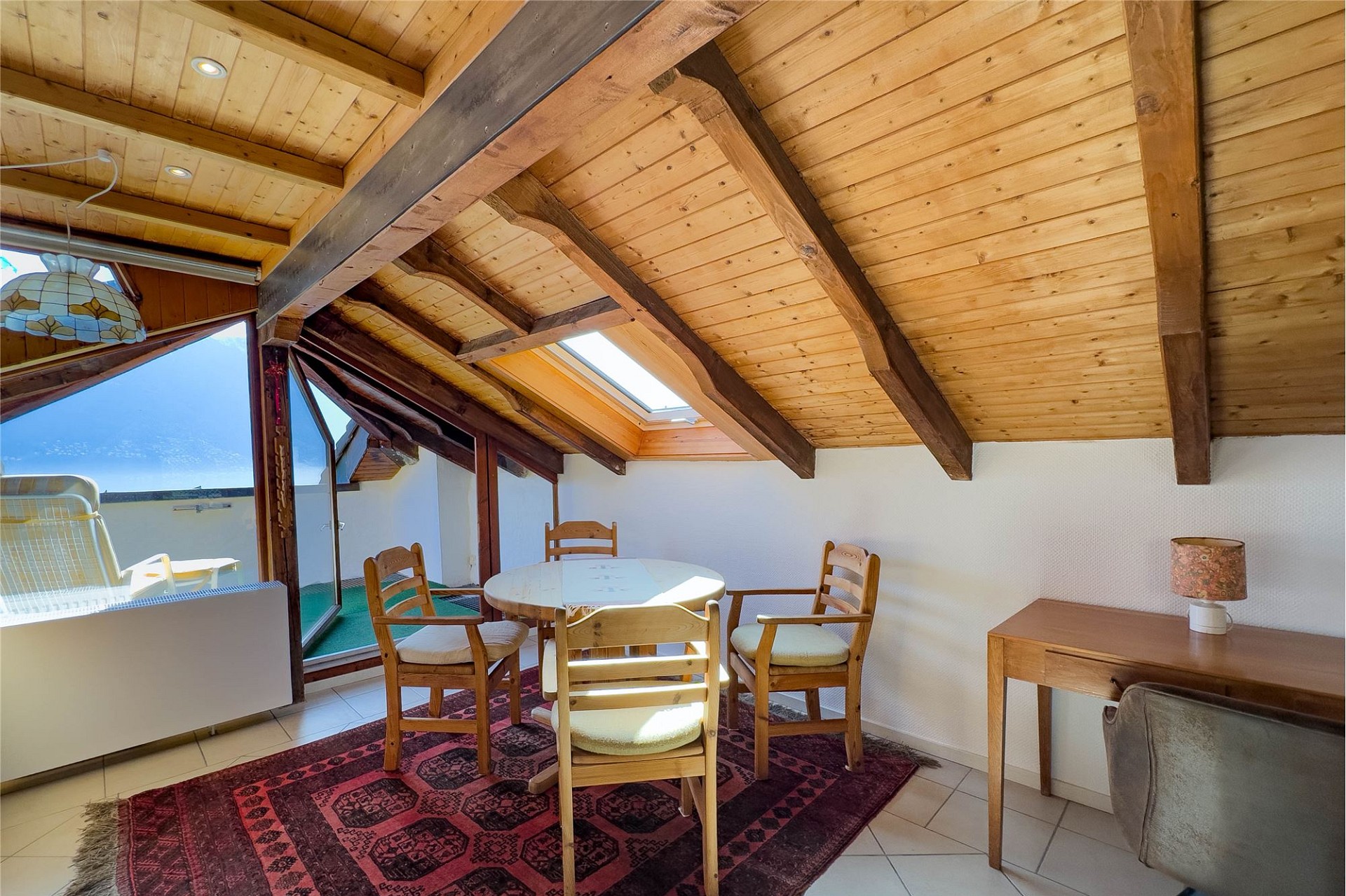 Dachgeschosszimmer mit Holzbalken und Balkonblick