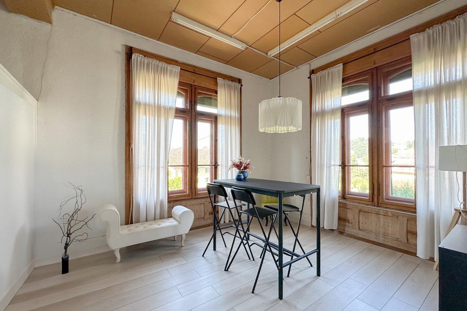 Heller Wohnraum mit großen Holzfenstern und Tisch