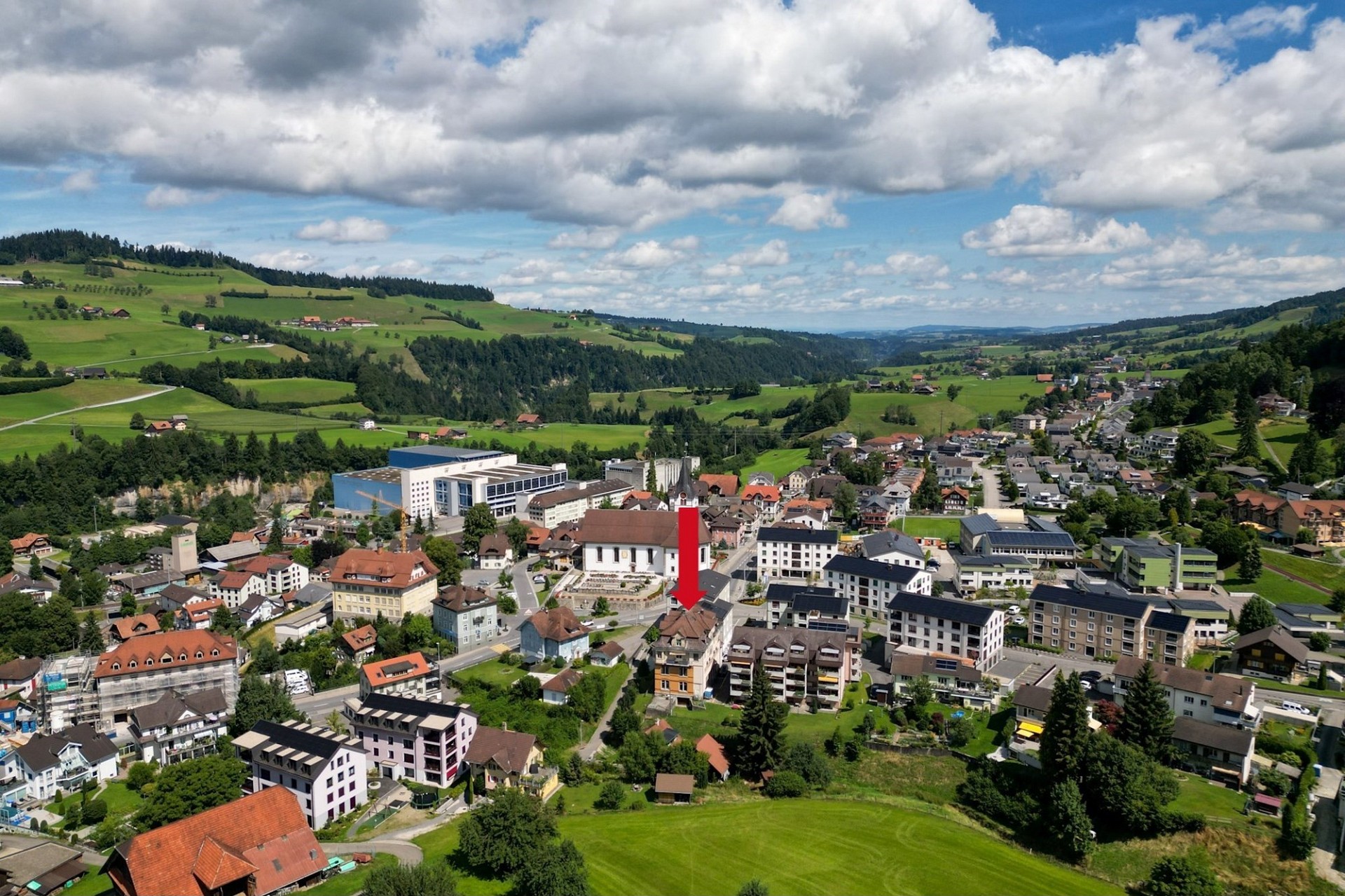 Luftaufnahme einer Alpen-Ortschaft mit markiertem Gebäude