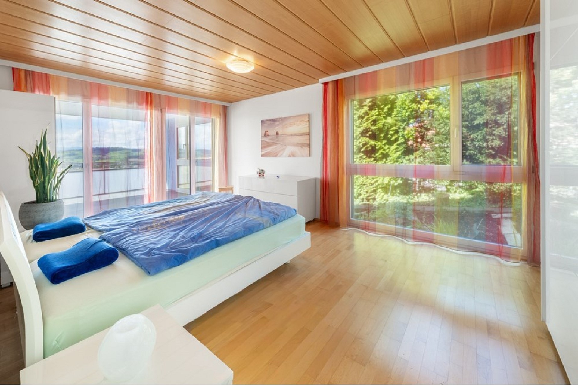 Helles Schlafzimmer mit Holzdecke und großen Fensterflächen