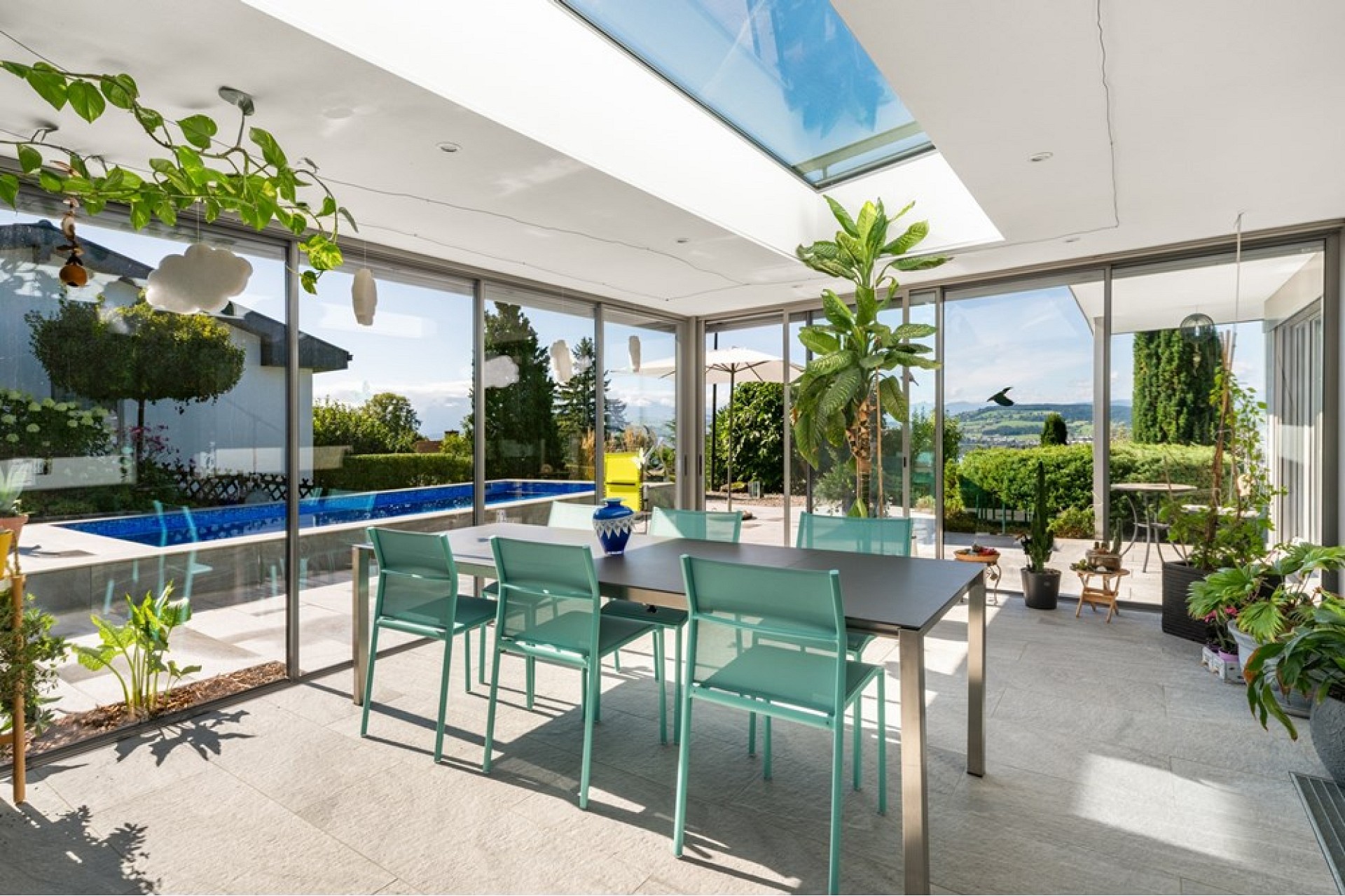 Verglaster Essbereich mit Poolblick