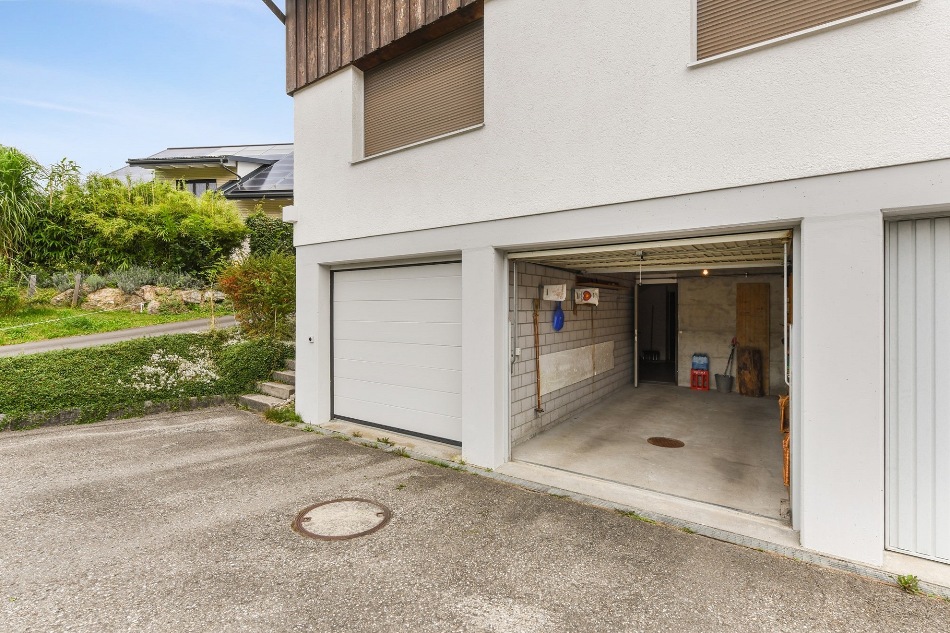 Garage mit Einfahrt und Gartenansicht