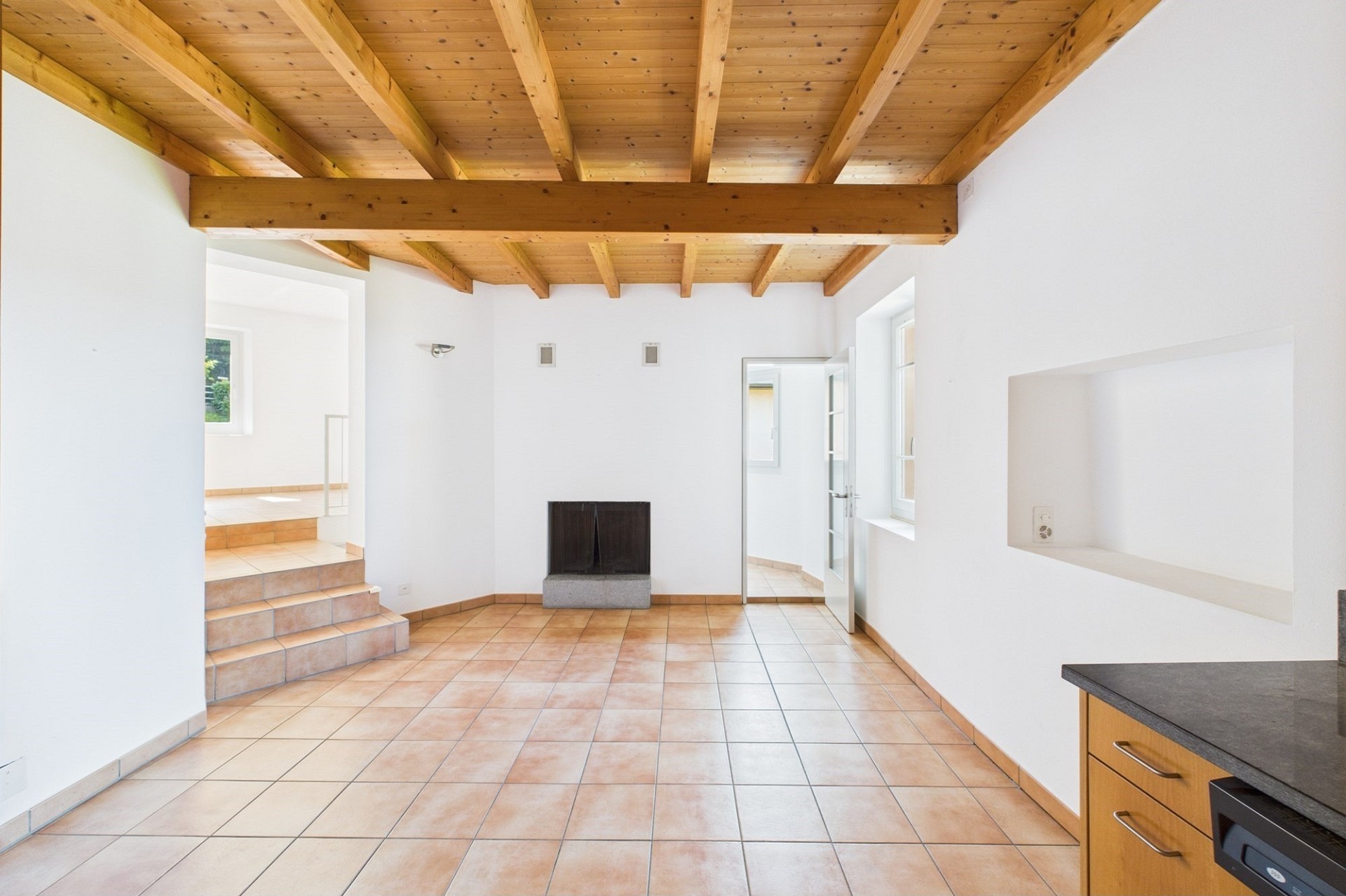Heller Raum mit sichtbaren Holzbalken und Kamin