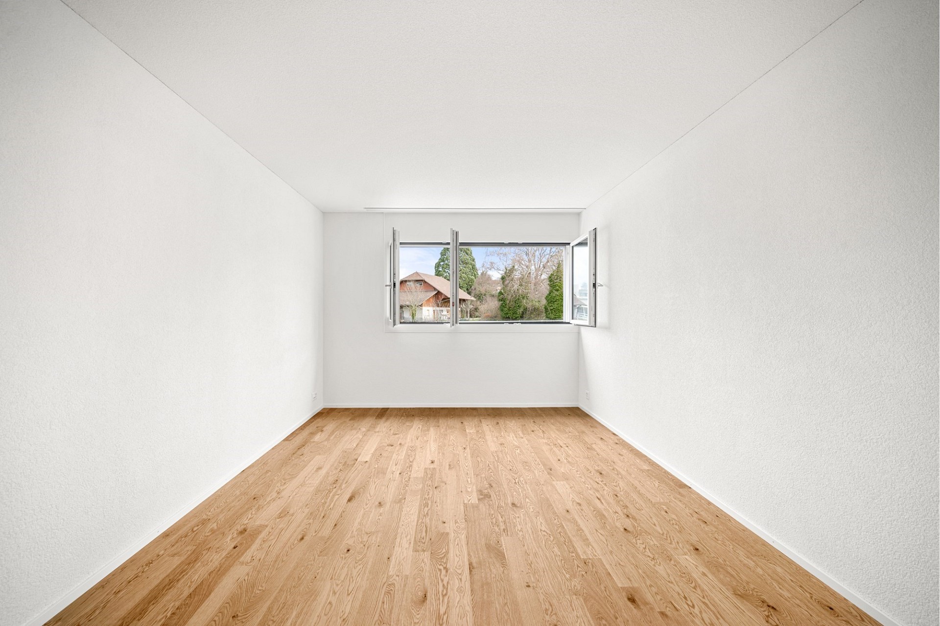 Heller leerer Raum mit Parkett und Fensterblick